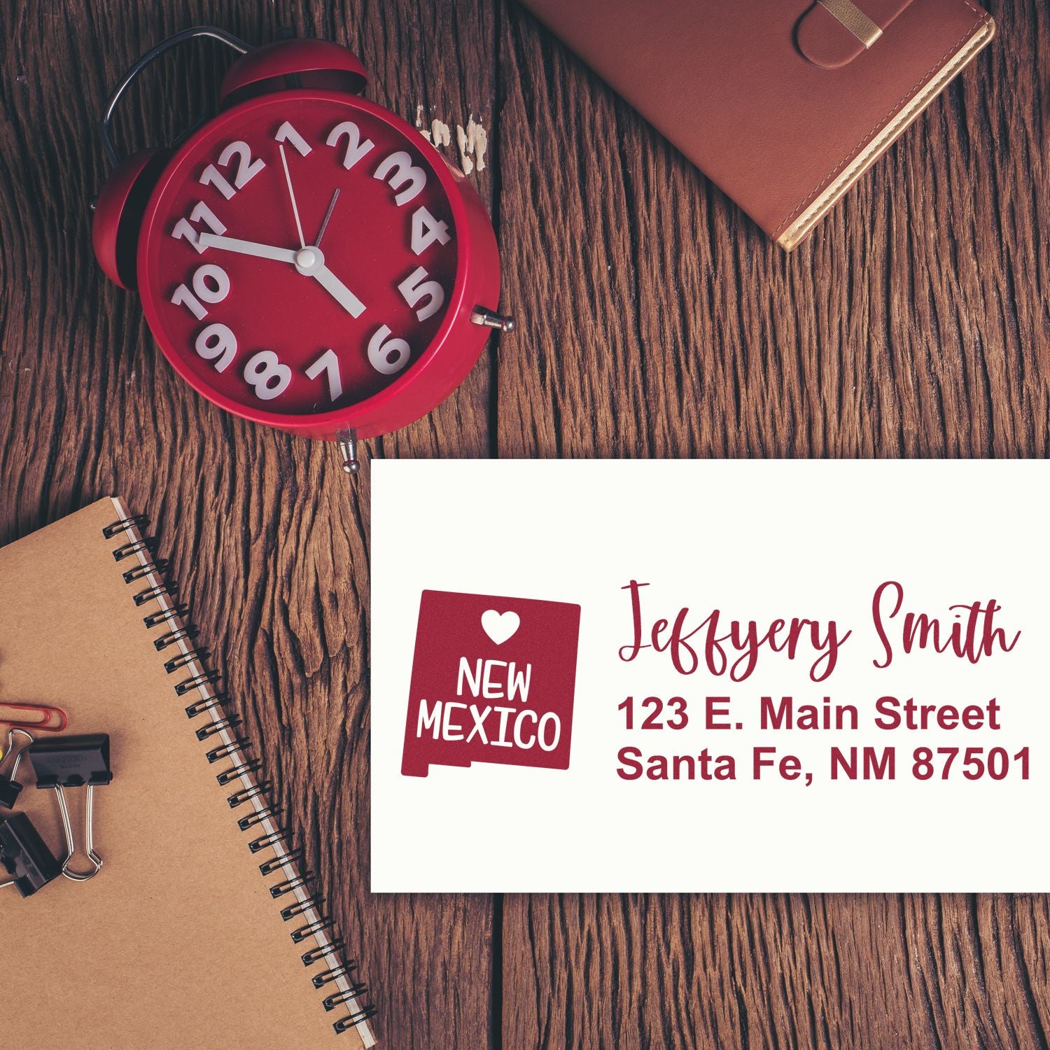 PSI Pre-Inked New Mexico State Love Customized Address Stamp on envelope with red clock and notebook on wooden desk.