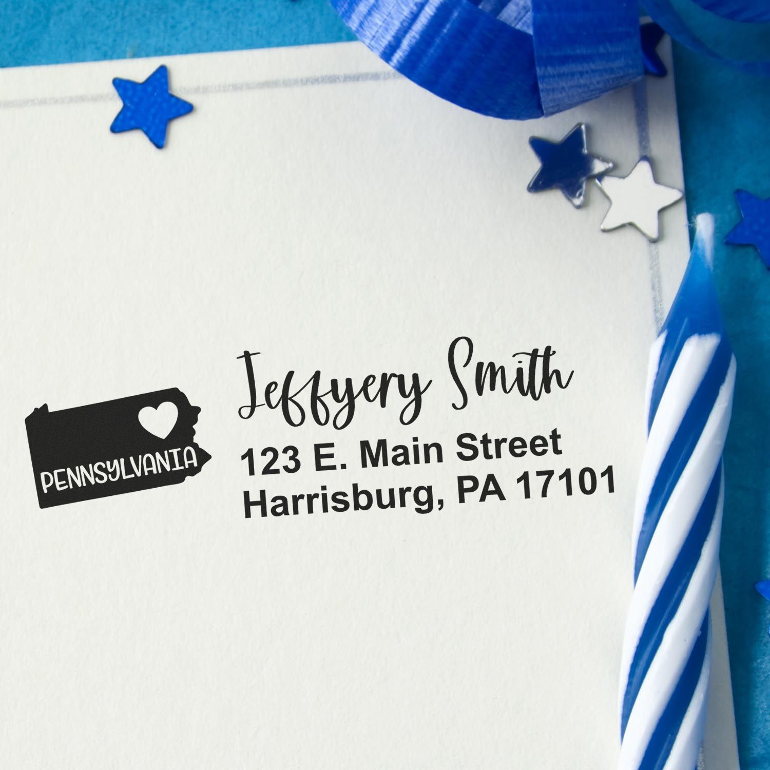 Pennsylvania State Love Personalized Address Stamp on an envelope with blue ribbon and stars. The stamp features a heart and state outline, displaying a name and address in stylish black font.