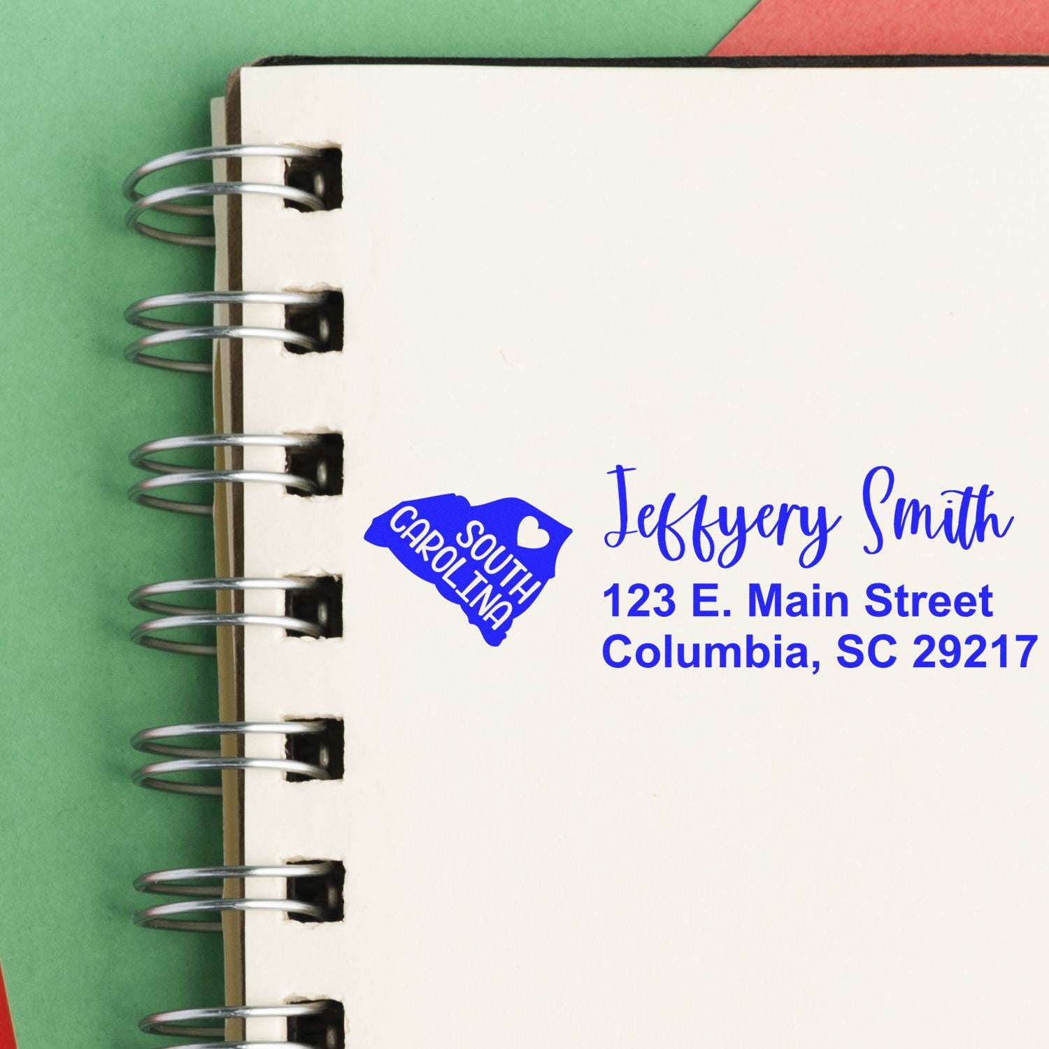 South Carolina State Love Personalized Address Stamp on a notebook, featuring a blue state outline with a heart and custom address text in blue ink.