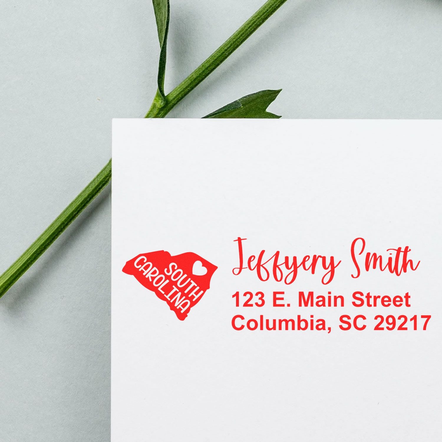 PSI Pre-Inked South Carolina State Love Customized Address Stamp on an envelope with a green stem, featuring a red state outline and address in red text.