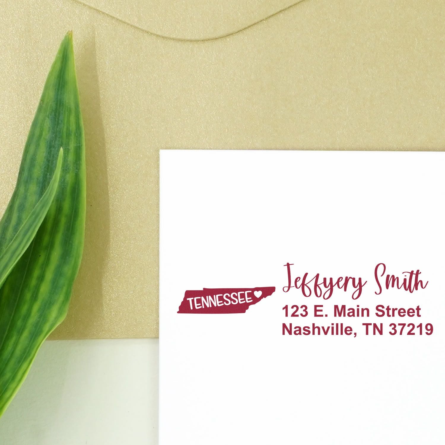 Tennessee State Love Personalized Address Stamp on a white envelope with a green leaf and beige background. The stamp features a red Tennessee state outline and personalized address details.