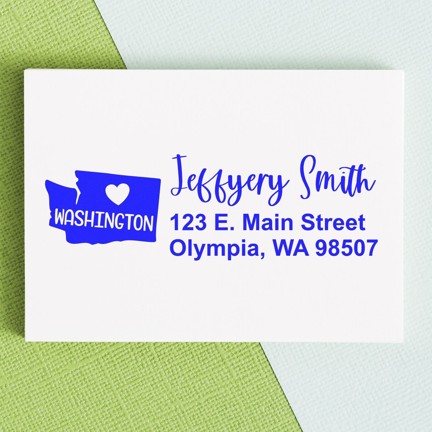 PSI Pre-Inked Washington State Love Customized Address Stamp on a white envelope with blue text, featuring a heart and state outline. Address reads: 123 E. Main Street, Olympia, WA 98507.