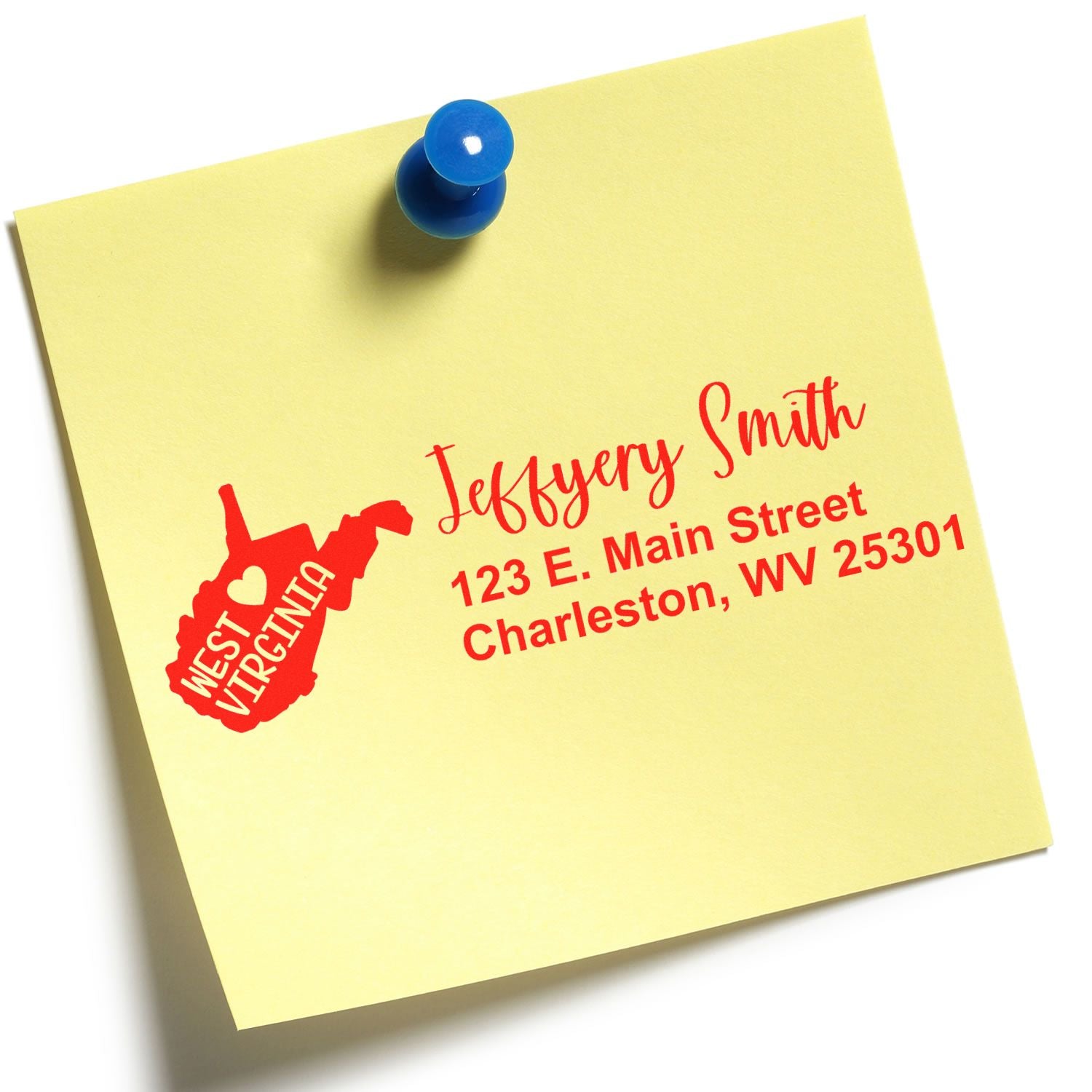 Yellow note with red text showing a custom address stamp design featuring West Virginia and an address. The Slim West Virginia Custom Address Stamp for Envelopes is pinned with a blue pushpin.