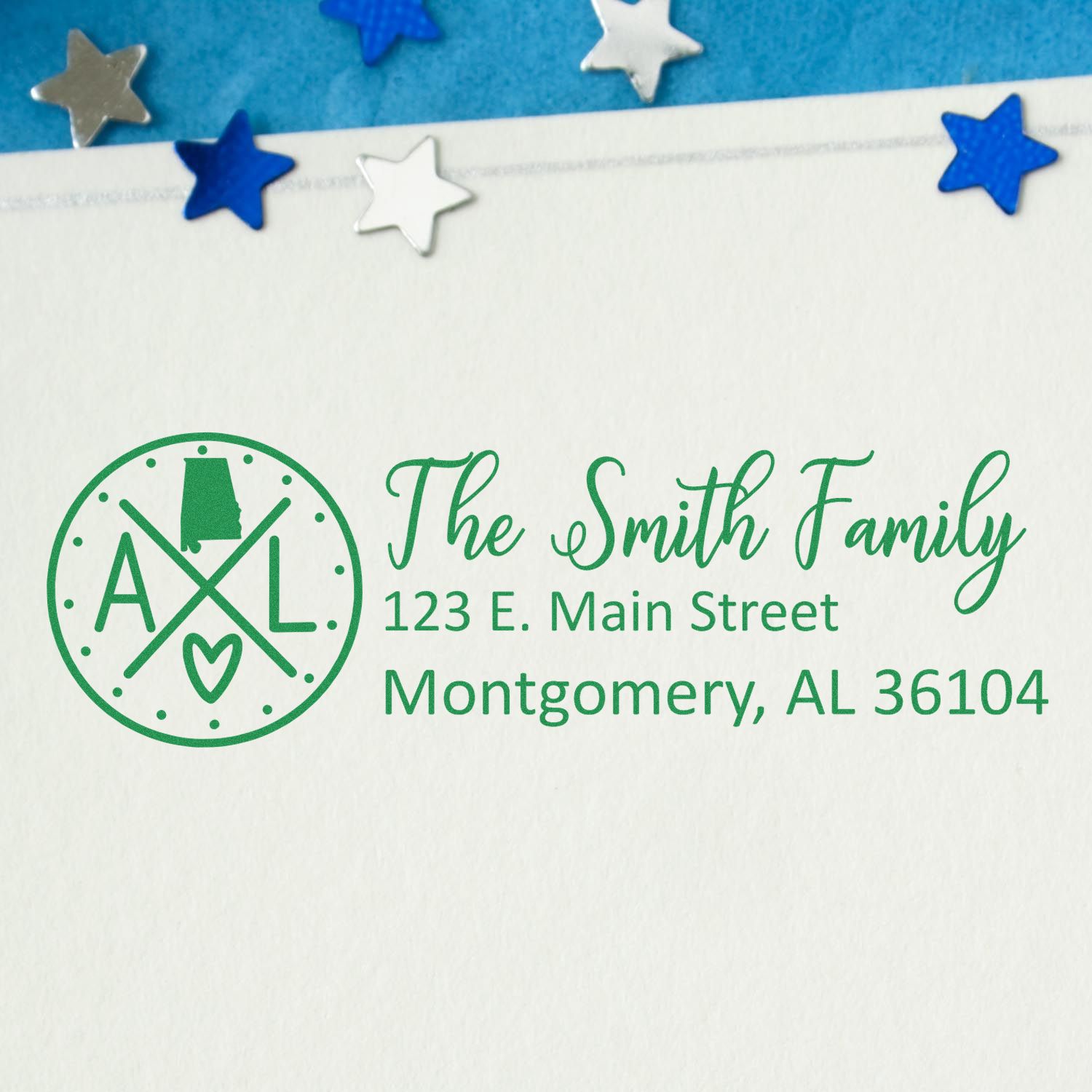 Alabama State Pride Customized Address Stamp featuring a green design with the state outline, initials AL, and a heart. Displays The Smith Family address on white paper with blue star confetti.