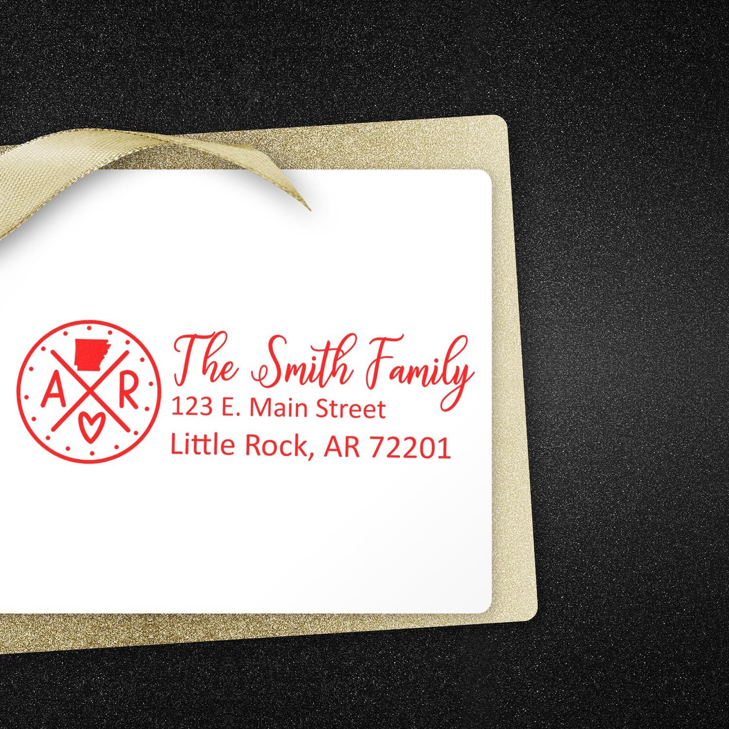 Arkansas State Pride Customized Address Stamp on a white card with red ink, featuring a family name and address, set against a glittery black and gold background.