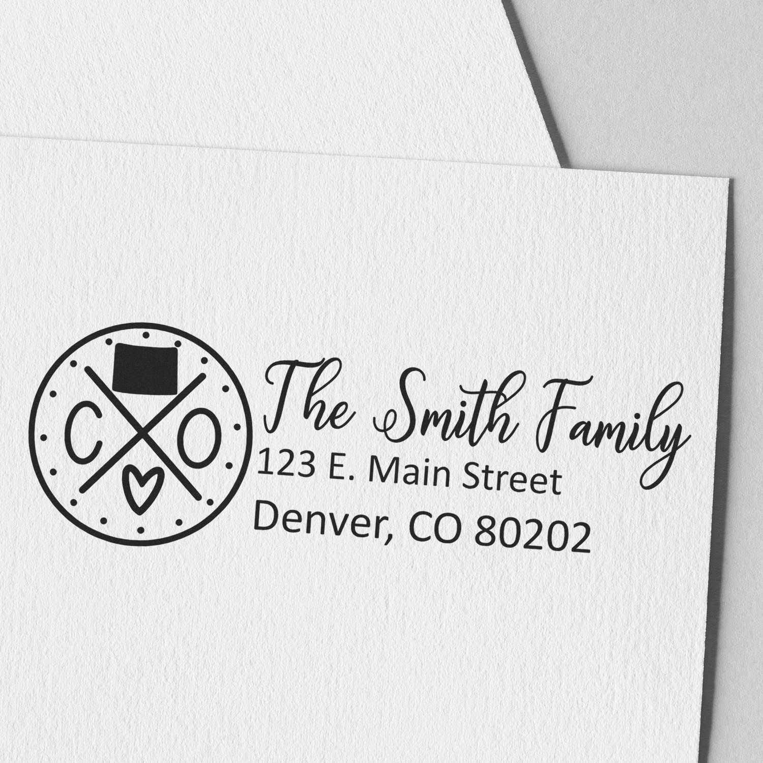 Image of the Colorado State Pride Customized Address Stamp on white paper, featuring a circular design with 'CO' and a heart, alongside personalized address details for the Smith Family in Denver.