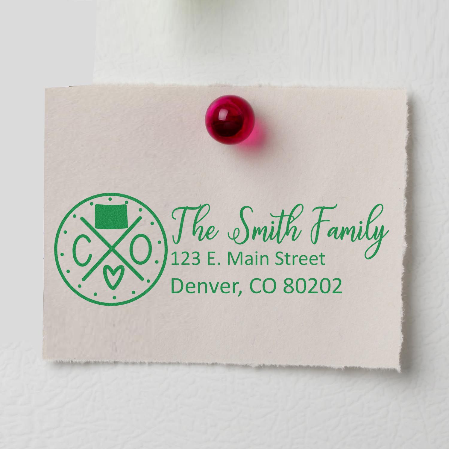 Colorado State Pride Customized Address Stamp on a note with The Smith Family, 123 E. Main Street, Denver, CO 80202 in green ink, pinned with a red pushpin.