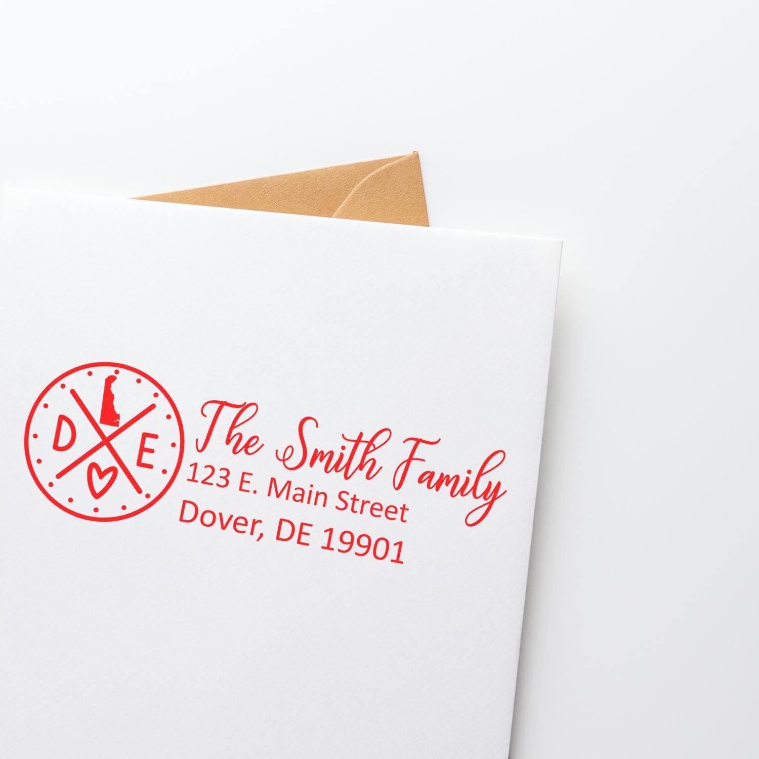 Slim Delaware Customized Pre-Inked Address Stamp in red ink on a white envelope, featuring a family name and address with a Delaware state icon.