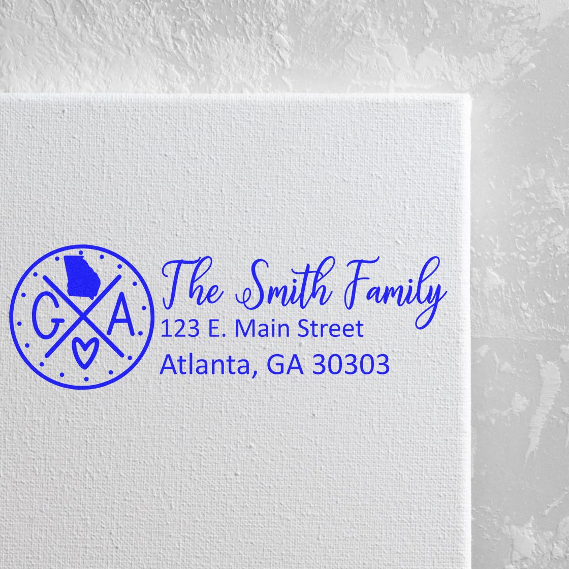 Self-Inking State Love of Georgia Custom Address Stamp on white paper, featuring a blue design with GA and a heart, personalized with The Smith Family and an Atlanta address.