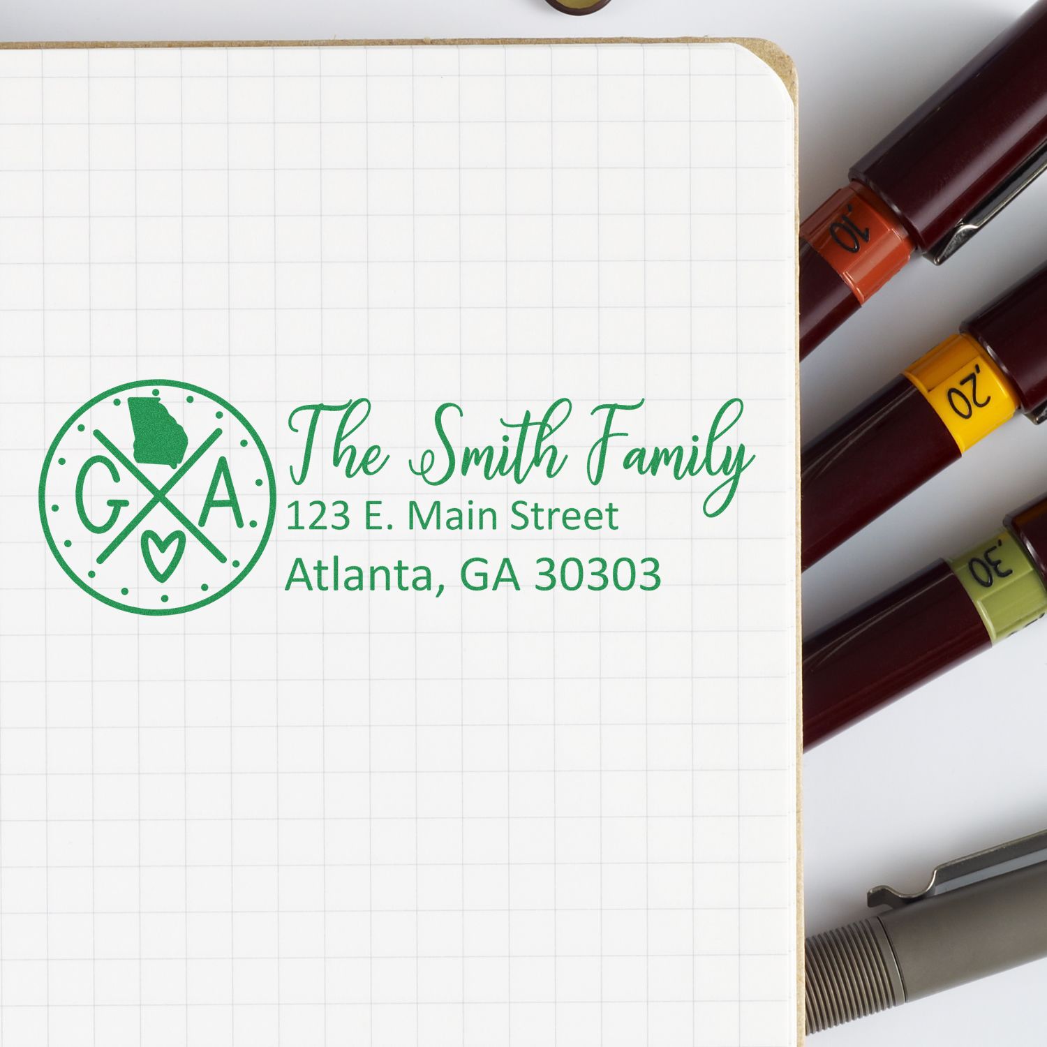 PSI Pre-Inked Georgia State Pride Customized Address Stamp on notepad with pens, featuring a Georgia outline and heart design, personalized with family name and address in green ink.