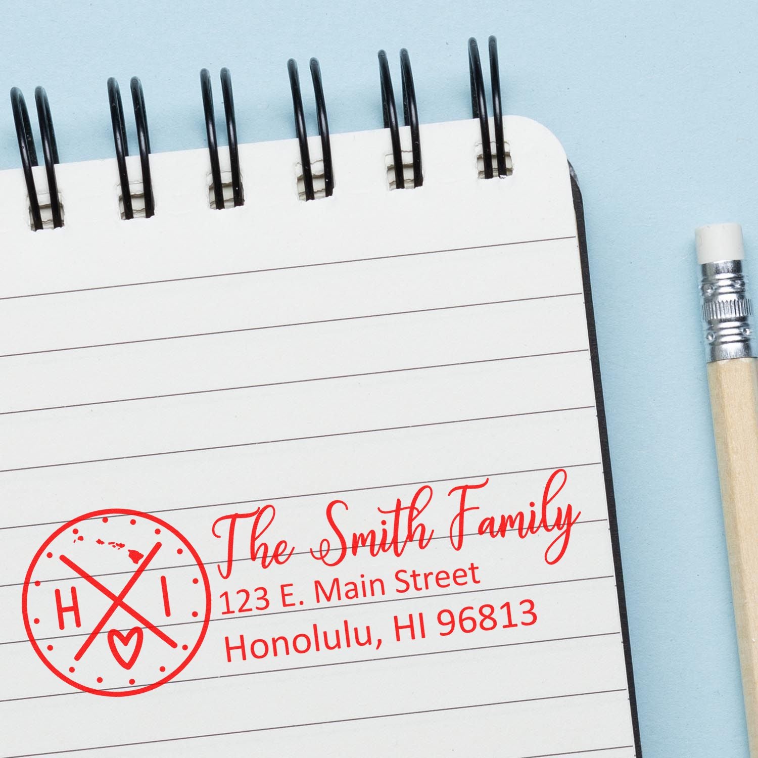 Hawaii State Pride Customized Address Stamp in red ink on a notebook page, featuring a circular design with HI and a heart, alongside a pencil.