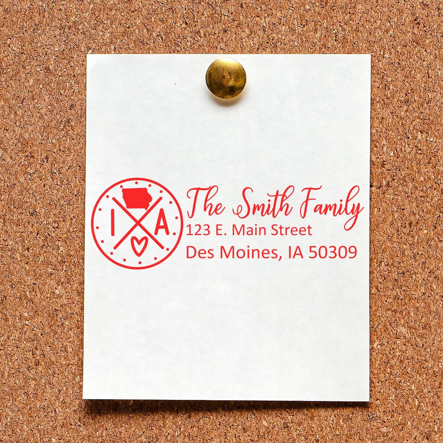 Iowa State Pride Customized Address Stamp on a corkboard, displaying The Smith Family, 123 E. Main Street, Des Moines, IA 50309 in red ink with a state-themed design.