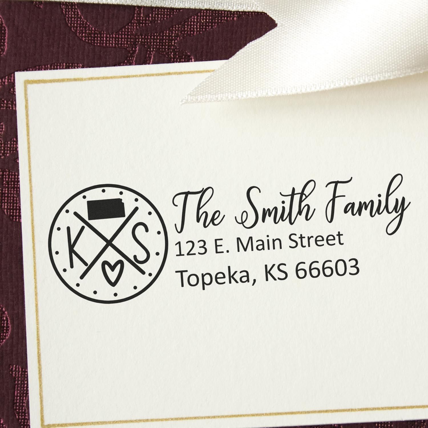 Slim Kansas Customized Pre-Inked Address Stamp on an envelope, displaying The Smith Family, 123 E. Main Street, Topeka, KS 66603 in elegant script, with a decorative KS logo.