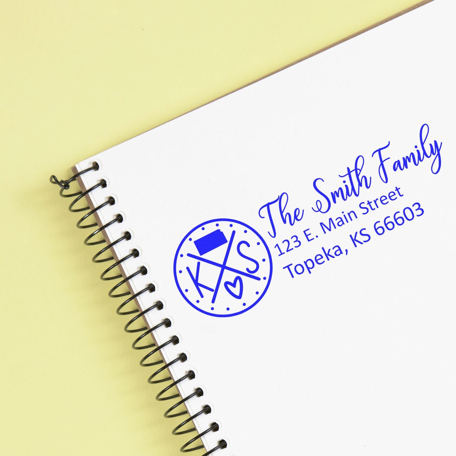 PSI Pre-Inked Kansas State Pride Customized Address Stamp on a notebook, displaying The Smith Family, 123 E. Main Street, Topeka, KS 66603 in blue ink with a Kansas-themed design.