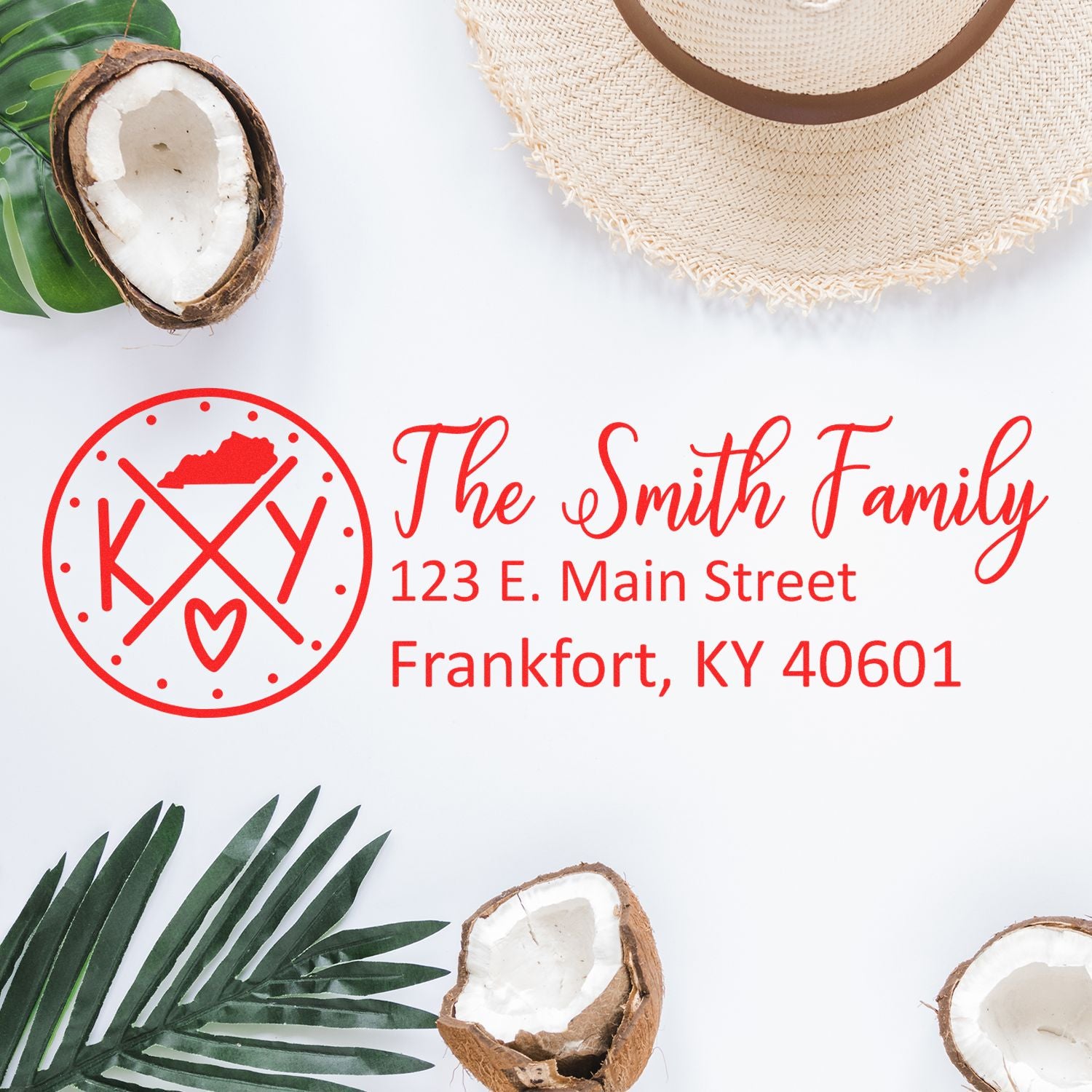 Slim Kentucky Customized Pre-Inked Address Stamp displayed on a white surface with a hat, coconut shells, and palm leaves, showcasing a personalized address in red ink.