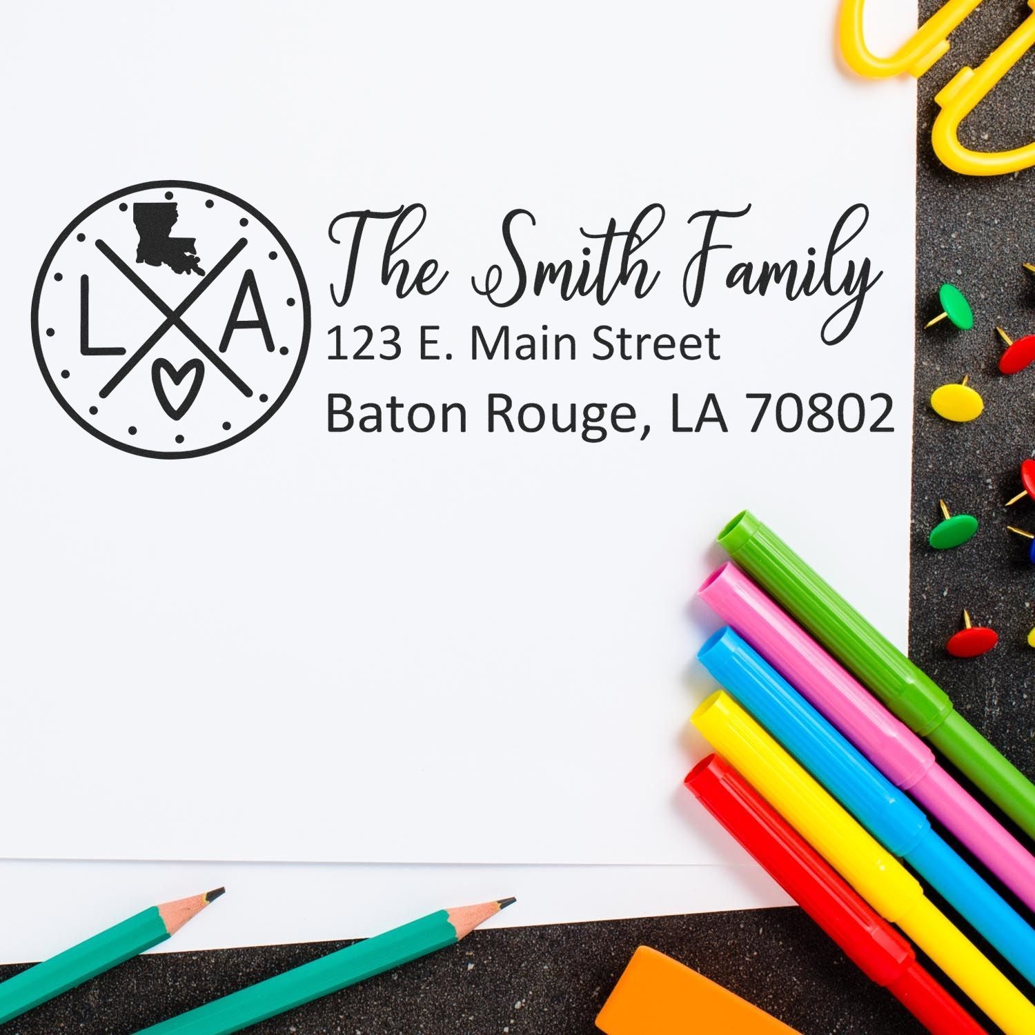 PSI Pre-Inked Louisiana State Pride Customized Address Stamp on white paper with colorful pens and push pins, featuring a Louisiana map and personalized address for The Smith Family in Baton Rouge.