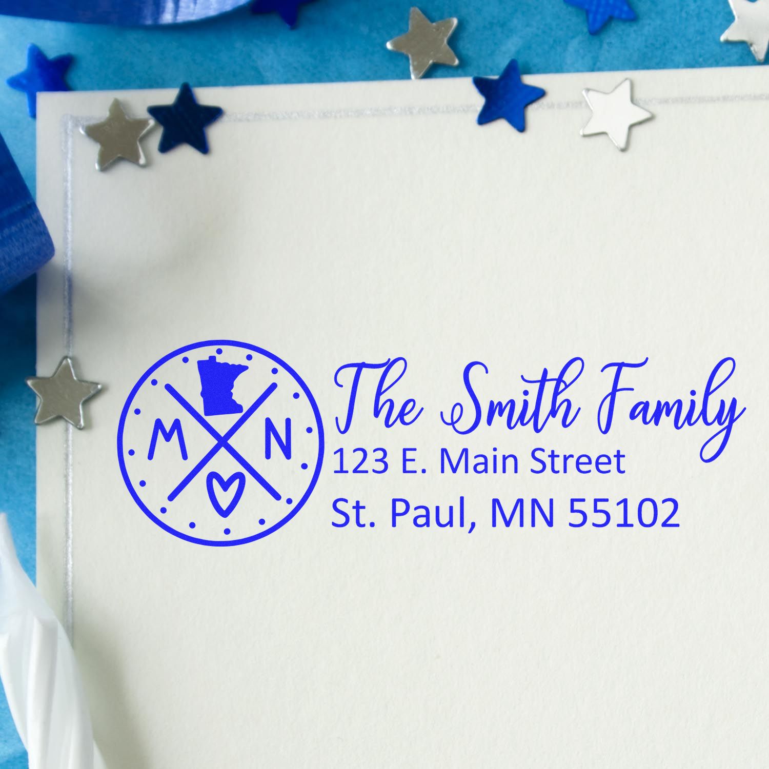 Minnesota State Pride Customized Address Stamp on an envelope with blue ink, surrounded by silver and blue star decorations.