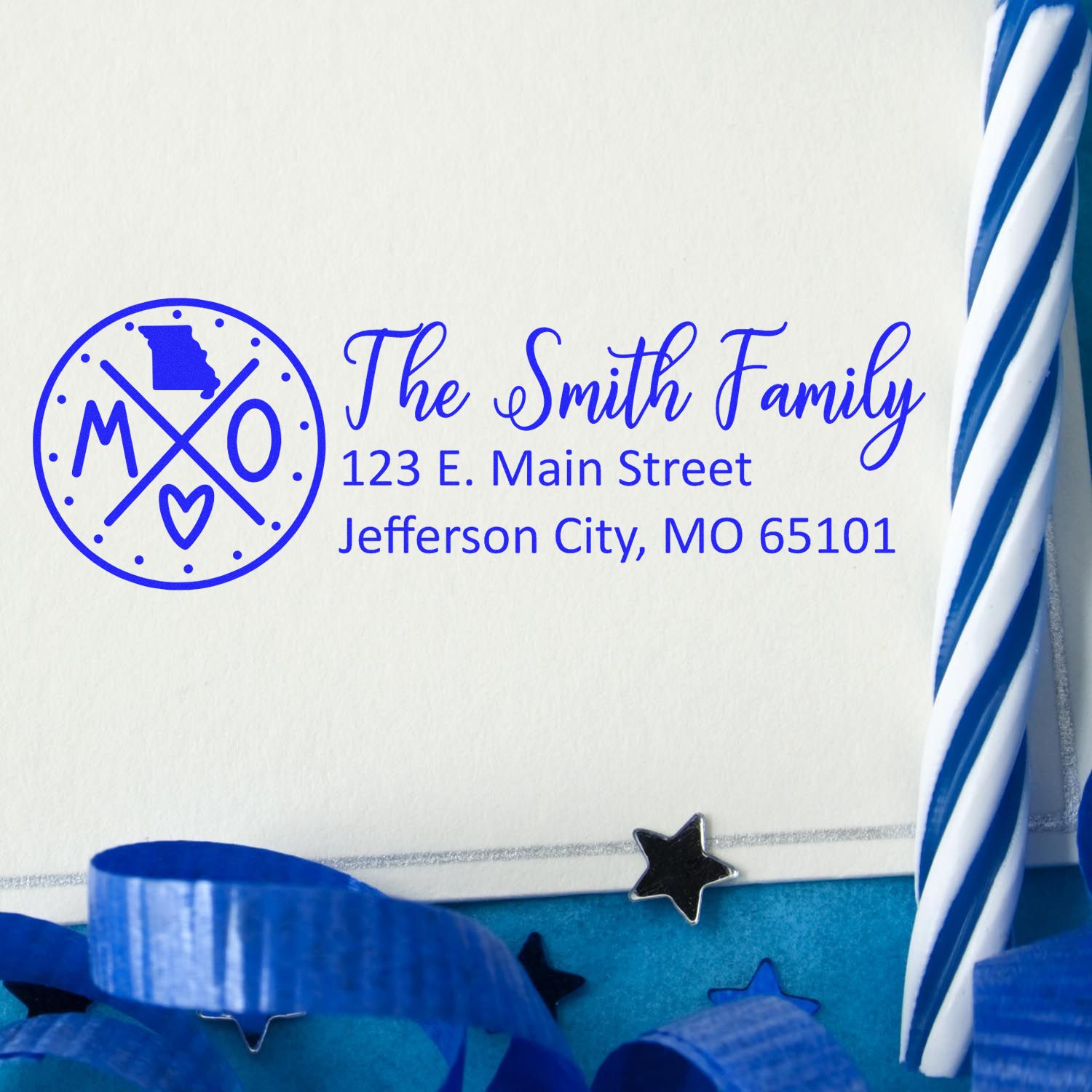 PSI Pre-Inked Missouri State Pride Customized Address Stamp on an envelope with blue ribbon and star decorations, featuring a Missouri map and personalized address for The Smith Family in blue ink.