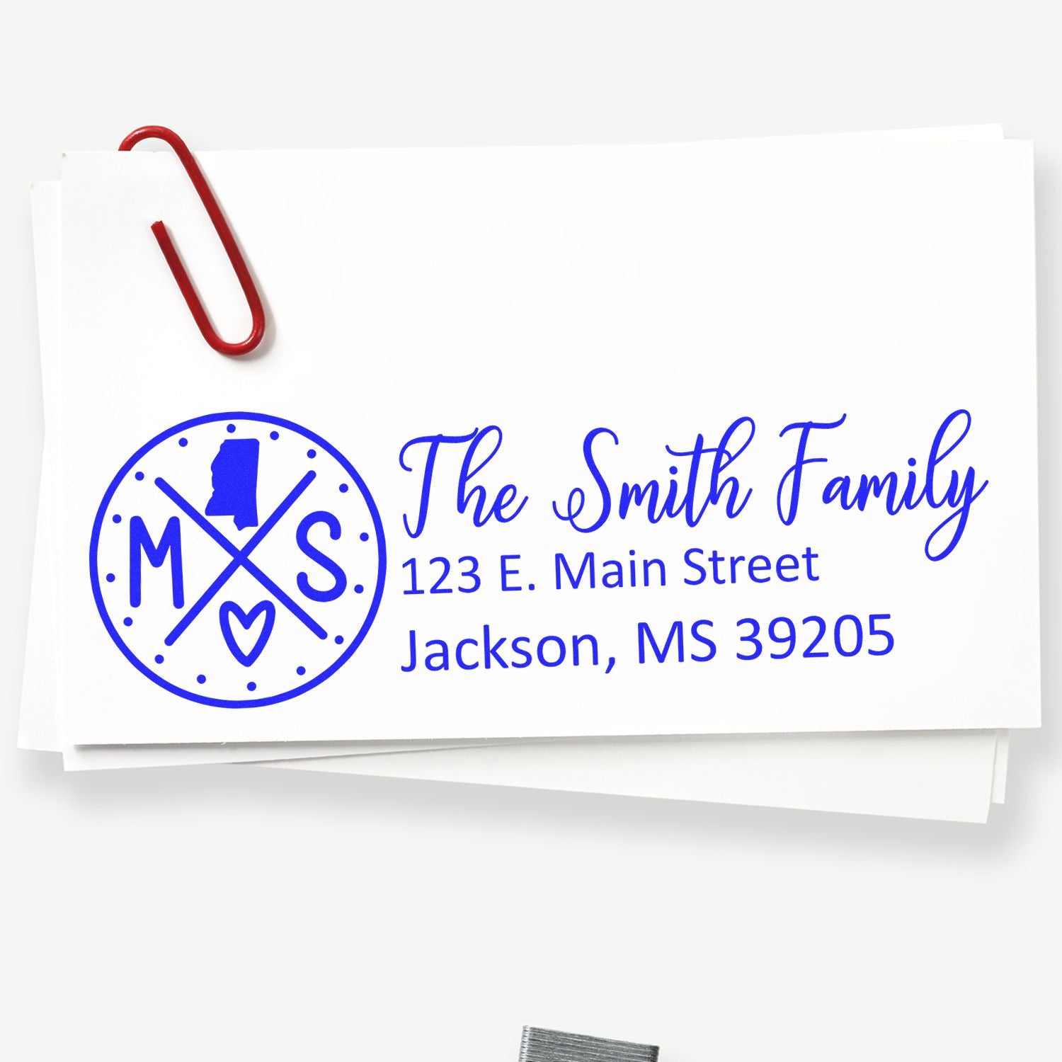 Mississippi State Pride Customized Address Stamp on white envelope with blue ink, featuring a circular design with MS and a heart. Red paperclip attached to the envelope.