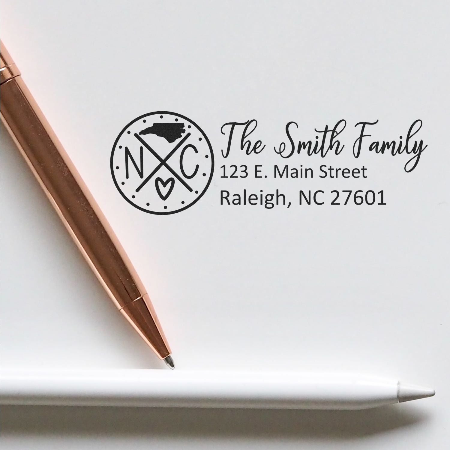 North Carolina State Pride Customized Address Stamp featuring The Smith Family with an NC design, shown on white paper with a rose gold pen and a white pencil.