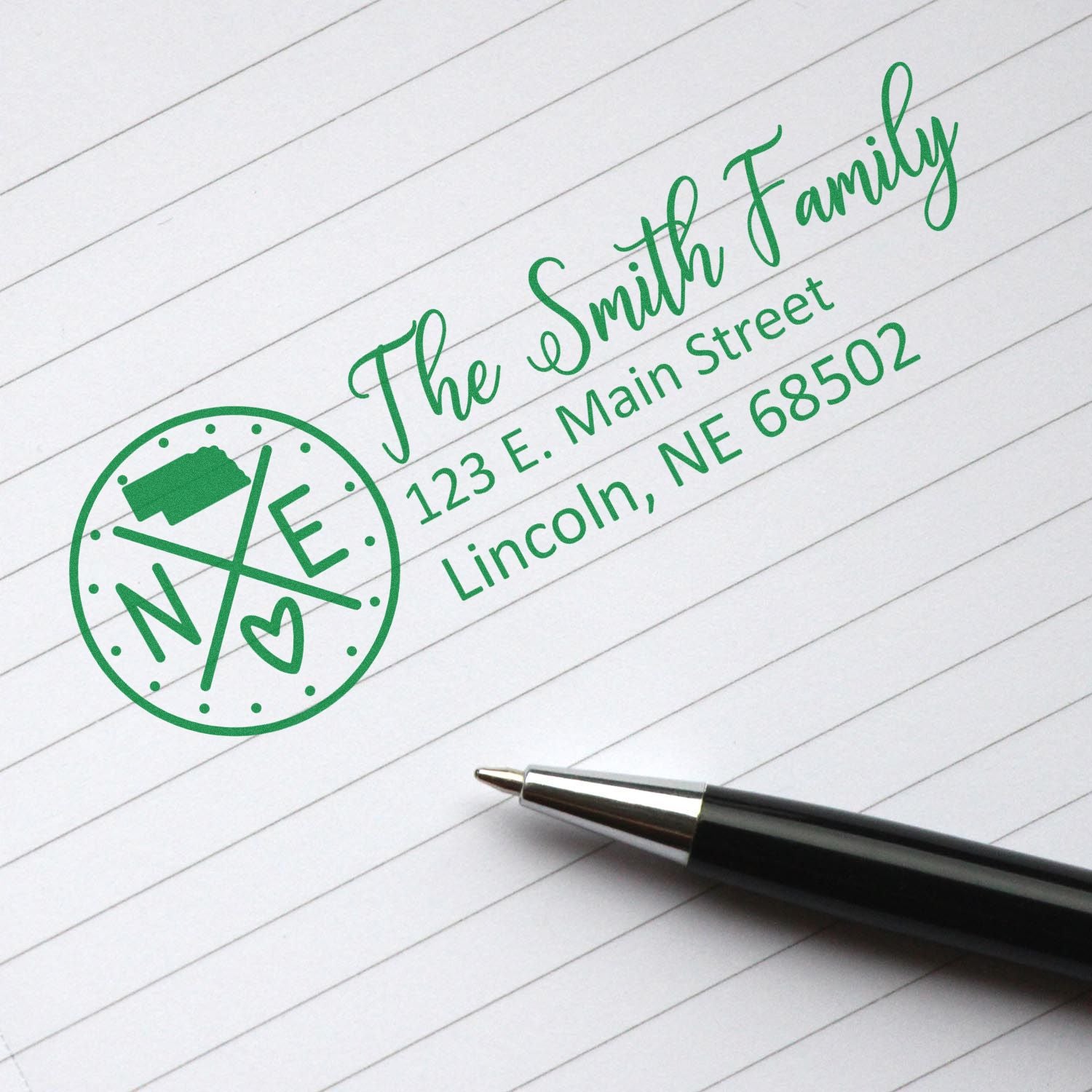 PSI Pre-Inked Nebraska State Pride Customized Address Stamp on lined paper, featuring a green design with a Nebraska map, heart, and address details. A pen lies nearby.