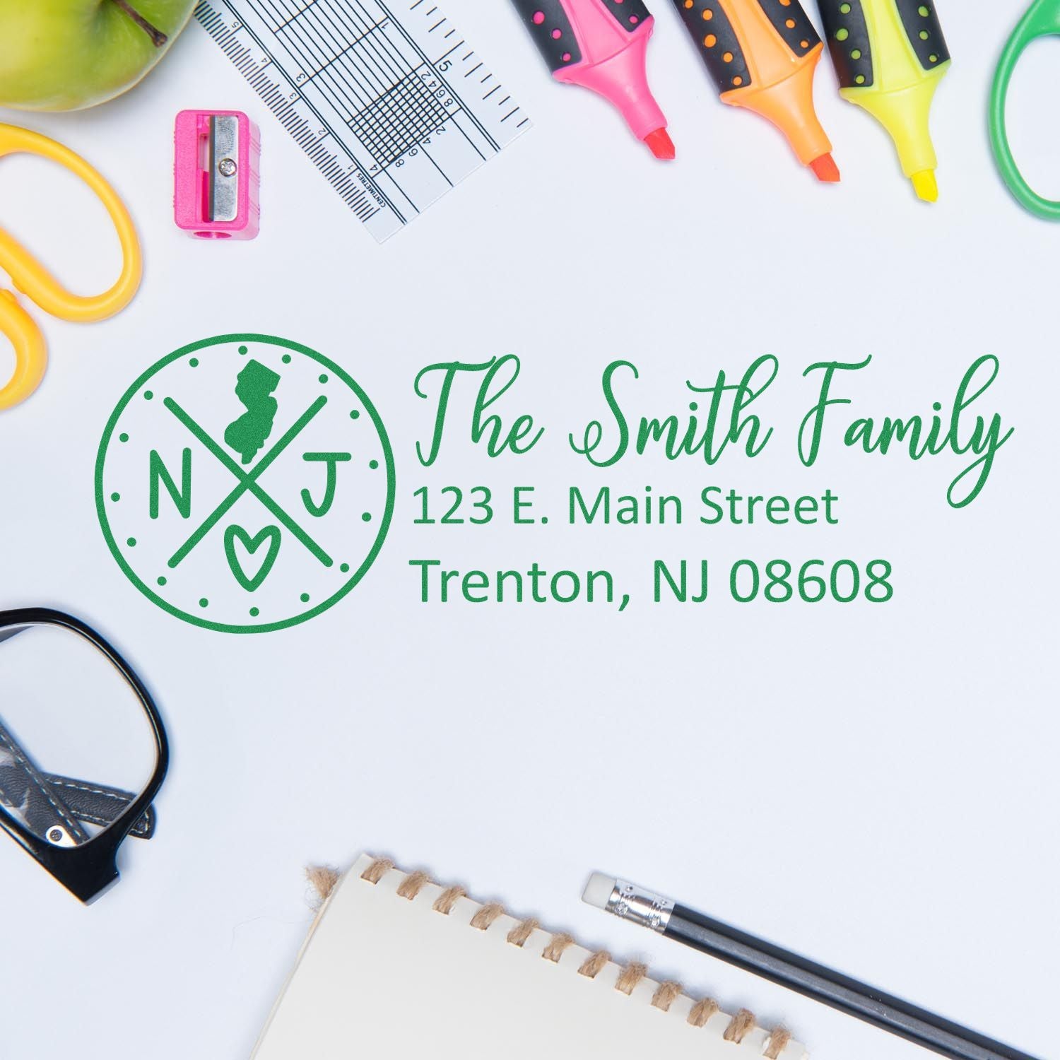 Slim New Jersey Customized Pre-Inked Address Stamp on a desk with stationery items, featuring a personalized address for the Smith Family in green ink.