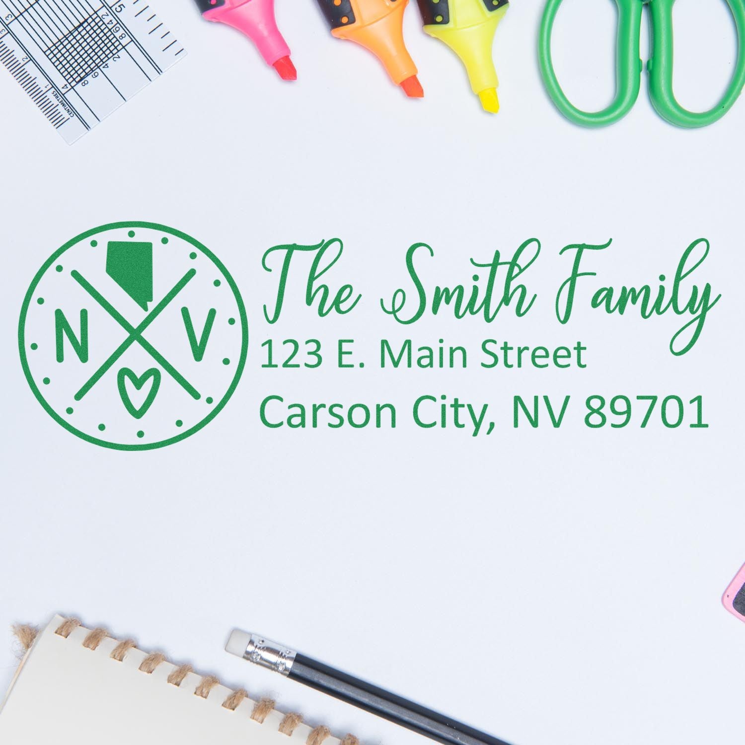 Slim Nevada Customized Pre-Inked Address Stamp showing 'The Smith Family, 123 E. Main Street, Carson City, NV 89701' in green ink on white paper, surrounded by office supplies.