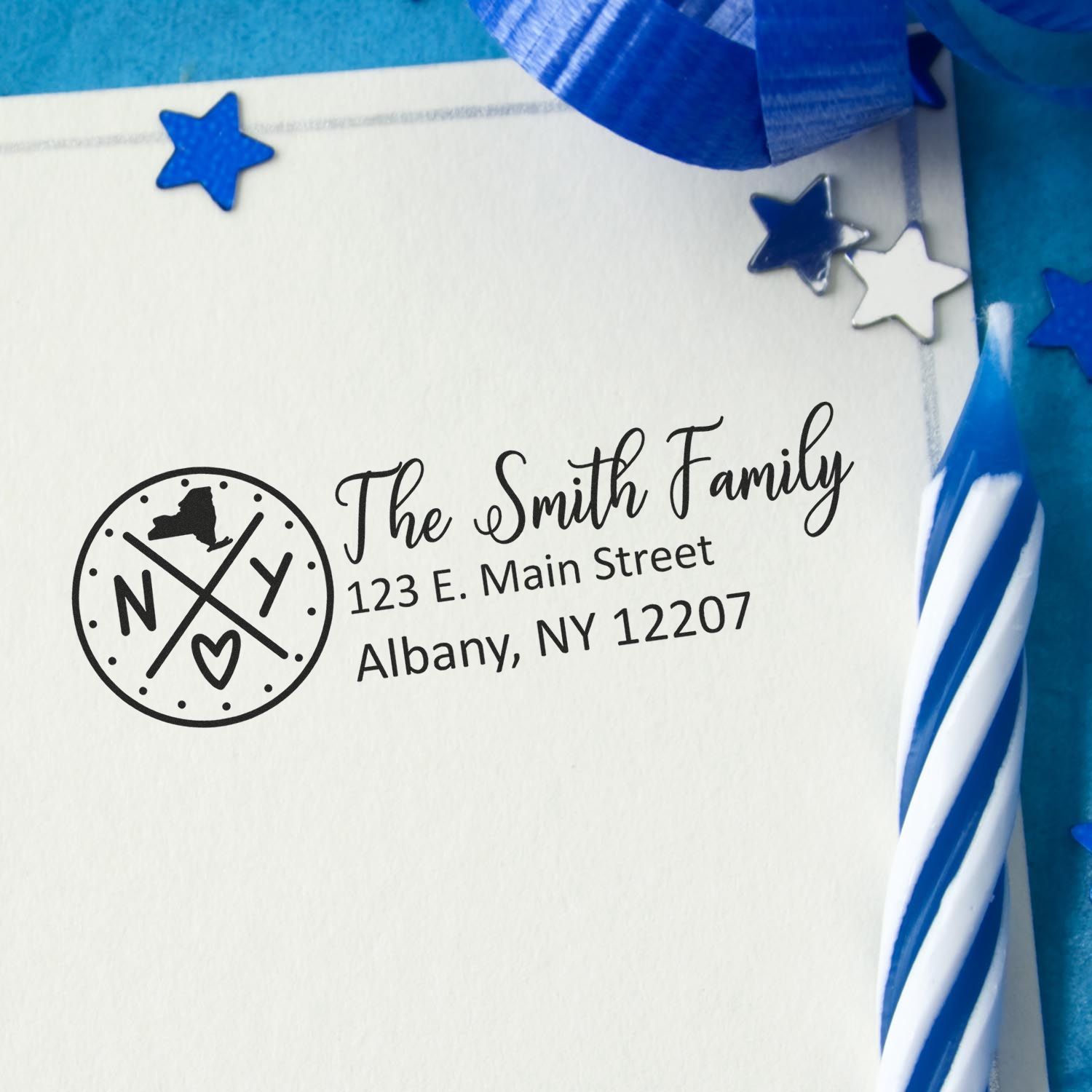 New York State Pride Customized Address Stamp on an envelope with blue stars and a striped candle, featuring a circular NY design and personalized address for the Smith Family in Albany, NY.