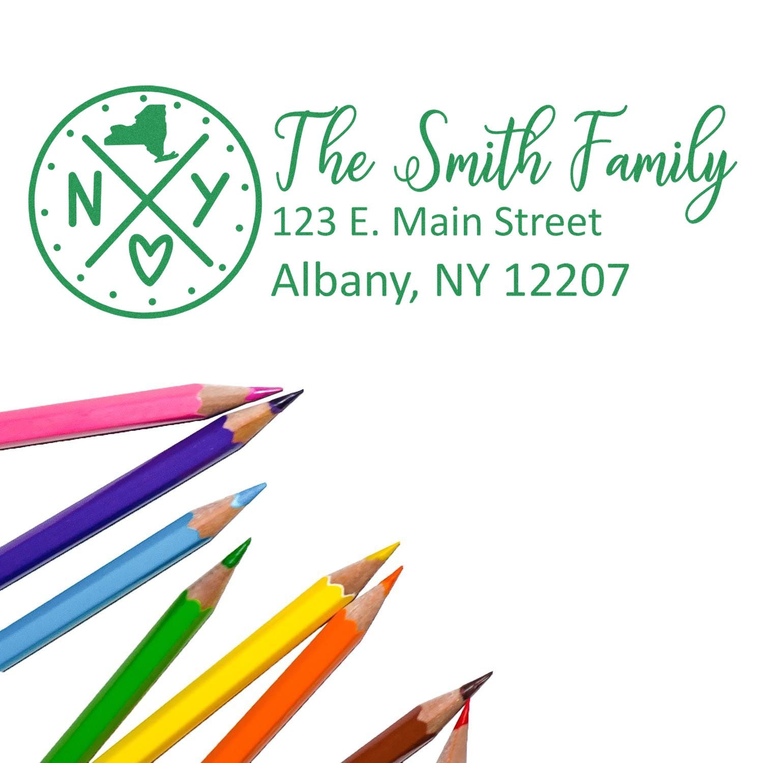 Colorful pencils beside a stamped envelope featuring the Slim New York Customized Pre-Inked Address Stamp with a family name and address in green ink, showcasing a stylish and personalized design.