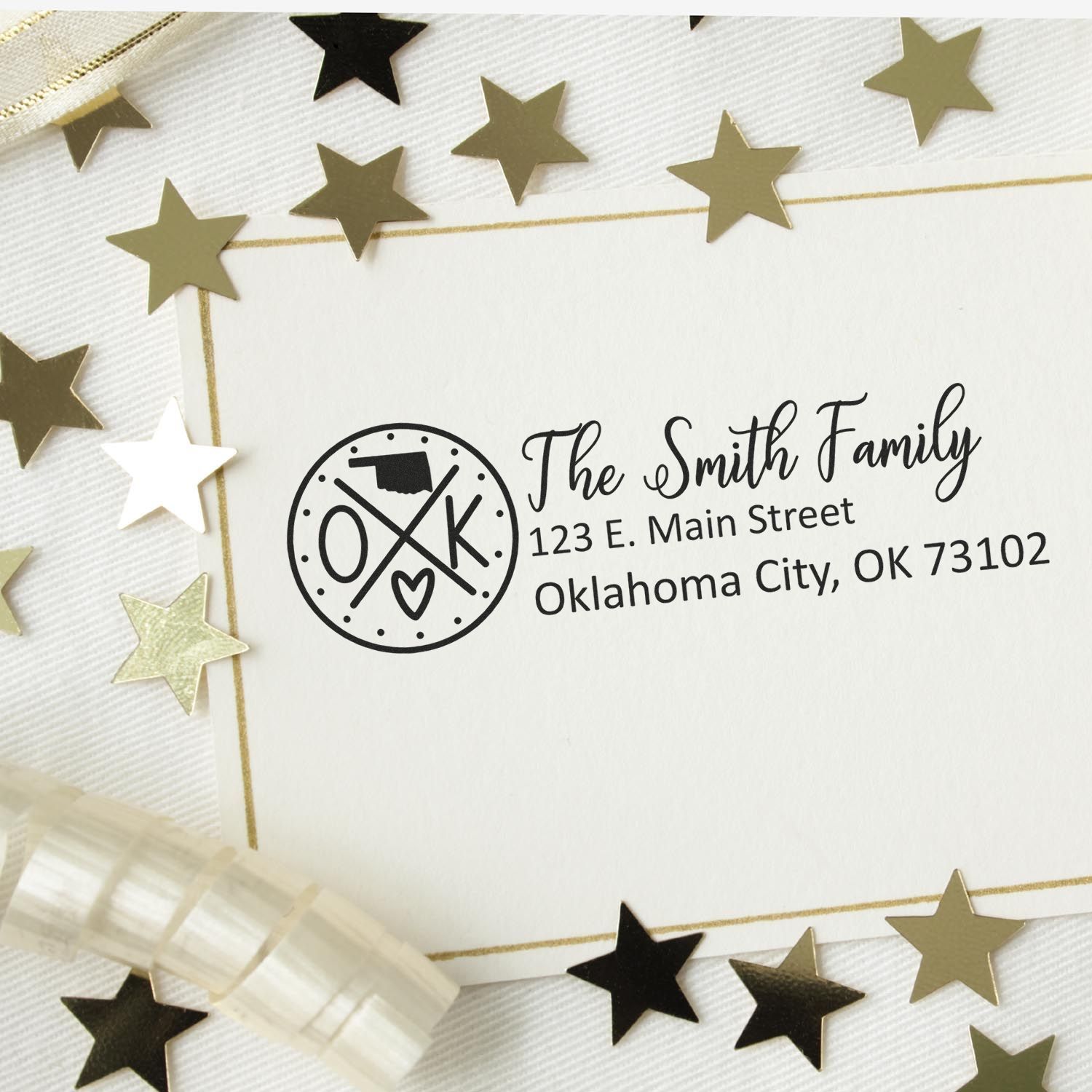 Self-Inking State Love of Oklahoma Custom Address Stamp on an envelope with gold star confetti. Displays The Smith Family, 123 E. Main Street, Oklahoma City, OK 73102 in elegant font.