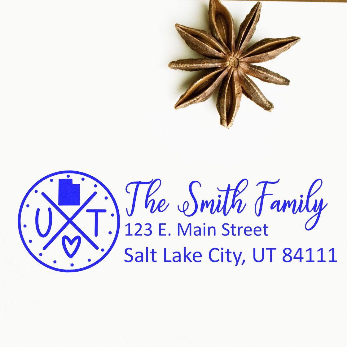 Slim Utah Customized Pre-Inked Address Stamp featuring a blue design with a Utah emblem and sample address for the Smith Family, displayed on white paper with a star anise decoration.