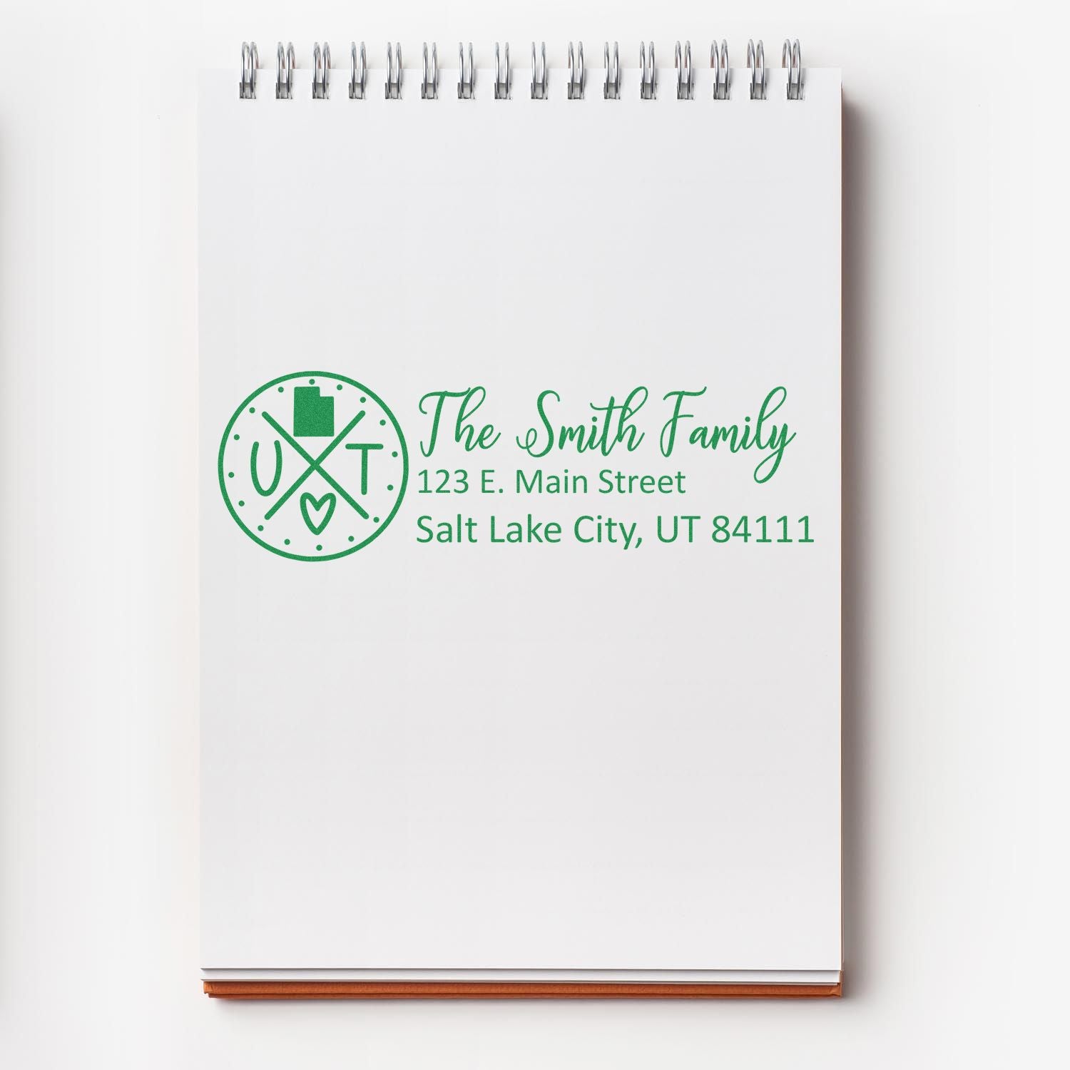 Utah State Pride Customized Address Stamp on a notepad, featuring a circular design with UT and a heart, alongside personalized address details for the Smith Family in green ink.