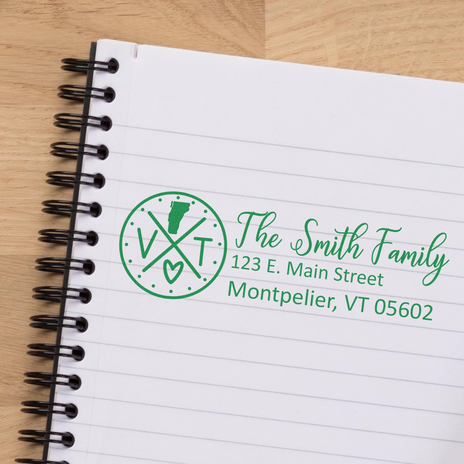 A Vermont State Pride Customized Address Stamp on a notebook page, featuring a green design with a map of Vermont, initials VT, and a heart, alongside a sample address for The Smith Family.