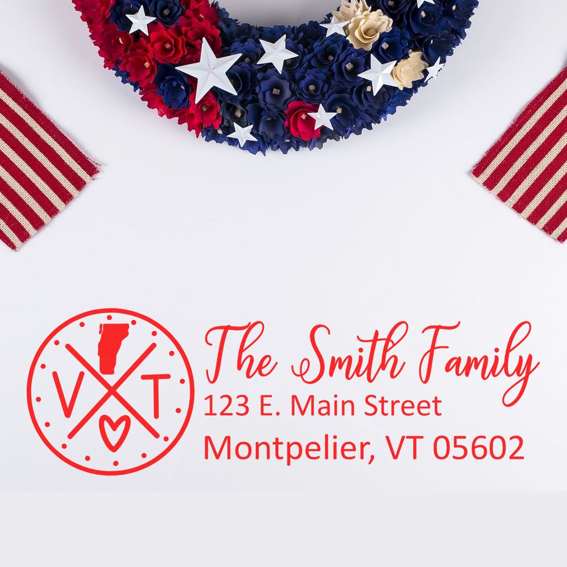 Red PSI Pre-Inked Vermont State Pride Customized Address Stamp with The Smith Family and Montpelier, VT address, set against a patriotic wreath and striped fabric background.