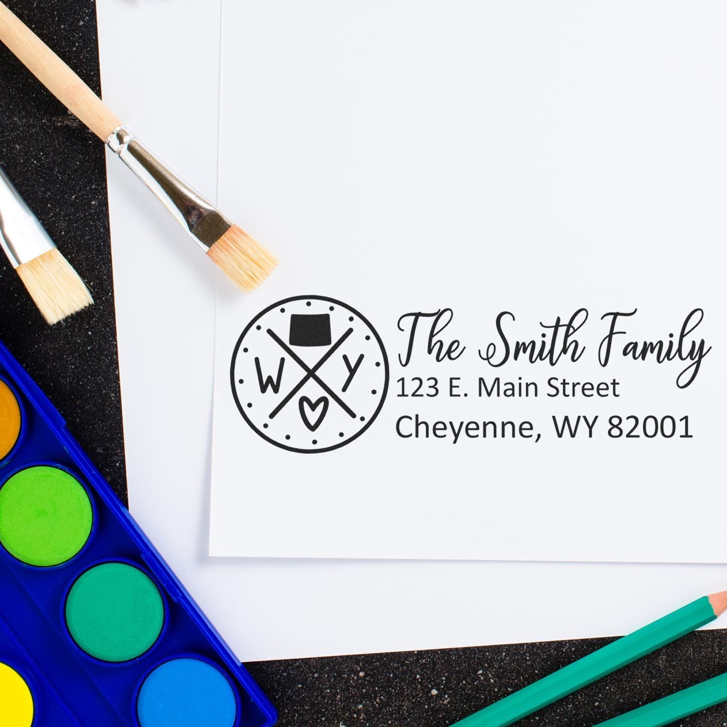 Wyoming State Pride Customized Address Stamp on white paper with paintbrushes and watercolor set nearby, featuring The Smith Family and a Wyoming-themed design.