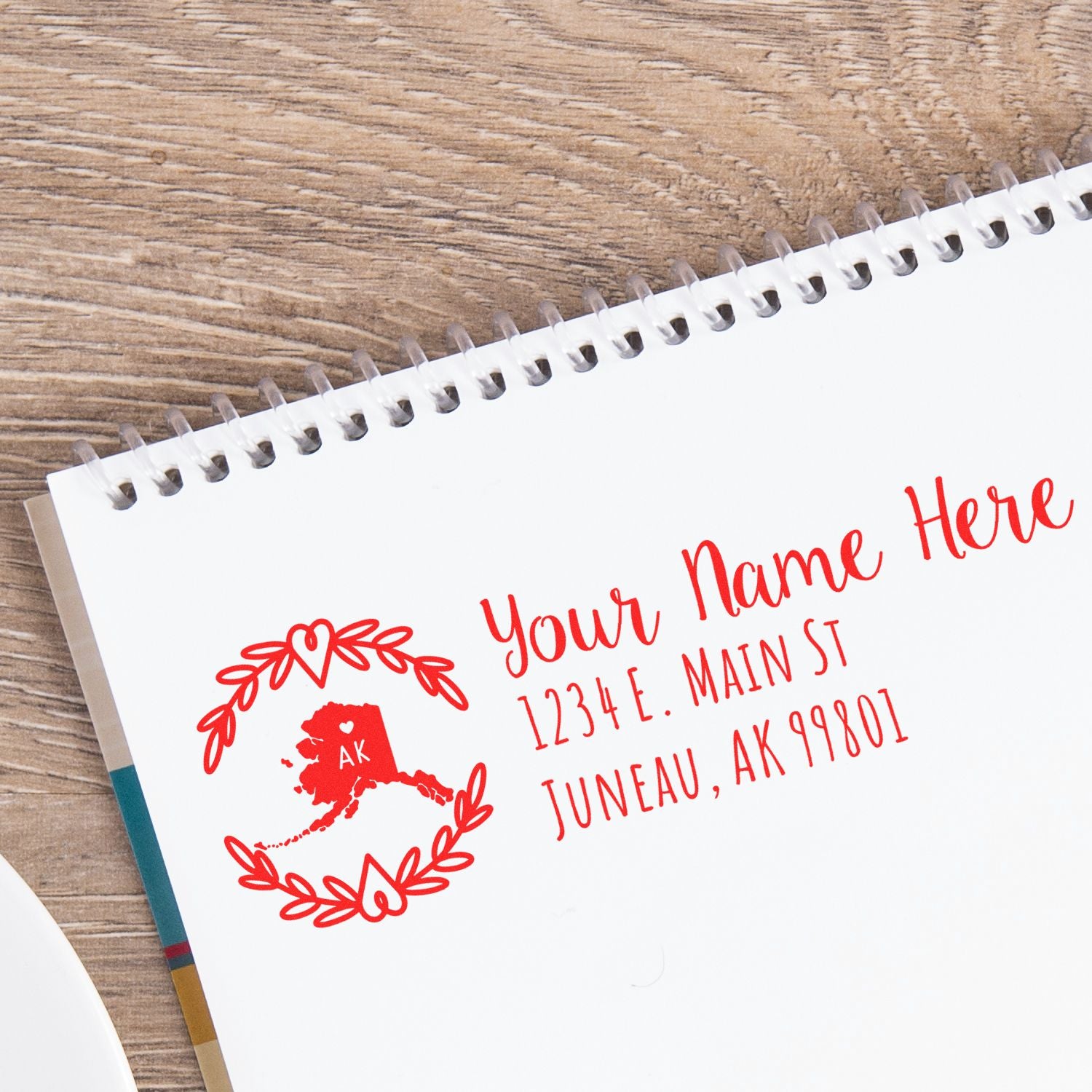 Alaska State Custom Return Address Stamp on a notebook, featuring a red design with the state outline and address details in elegant script.