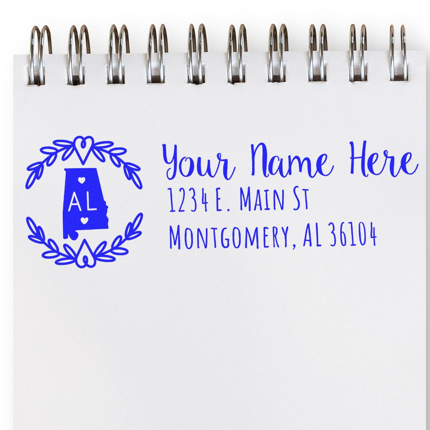 Self-Inking State Wreath of Alabama Address Stamp on notepad, featuring a blue Alabama outline with a wreath, personalized address, and elegant script.