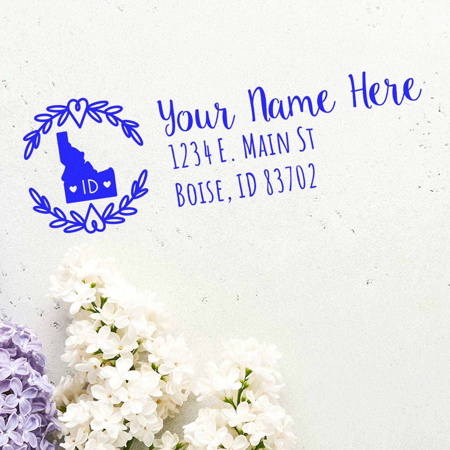 PSI Pre-Inked Idaho State Customized Address Stamp on white paper with floral border, featuring a blue Idaho map and sample address text.