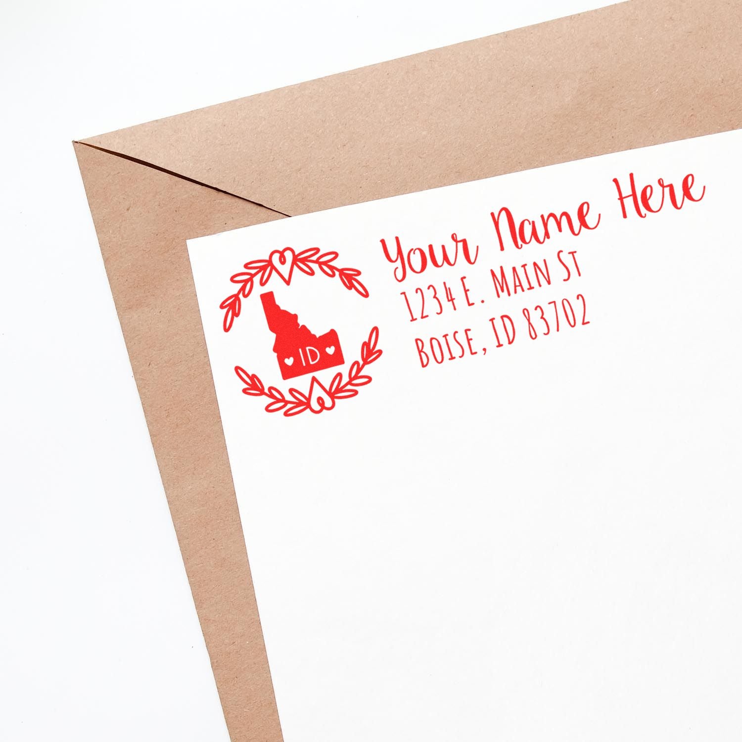 PSI Pre-Inked Idaho State Customized Address Stamp on a white envelope, featuring a red design with a state outline and laurel wreath, displaying a sample address in Boise, ID.