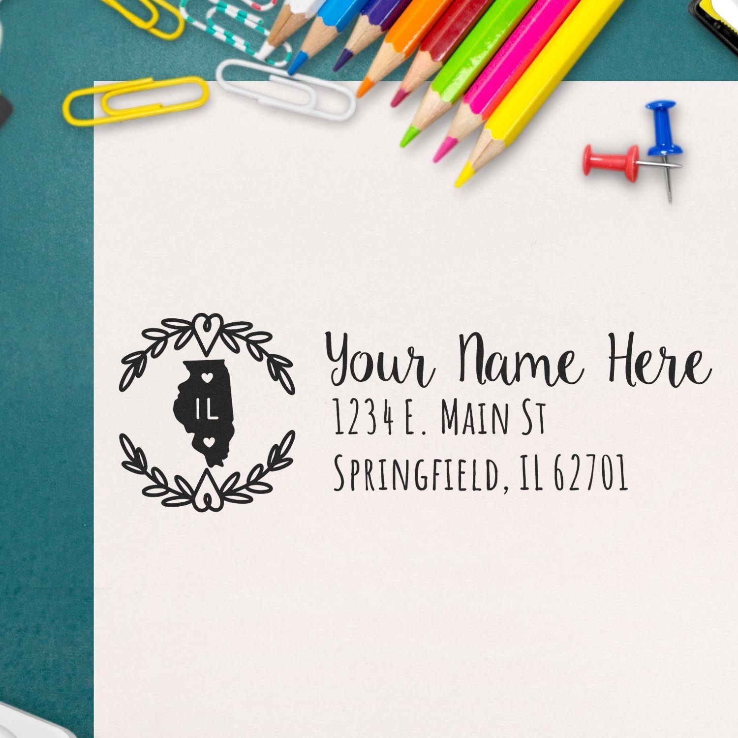 Illinois State Custom Return Address Stamp on paper with colorful pencils, paperclips, and pushpins. Features state outline and decorative border, ideal for personalized mailings.