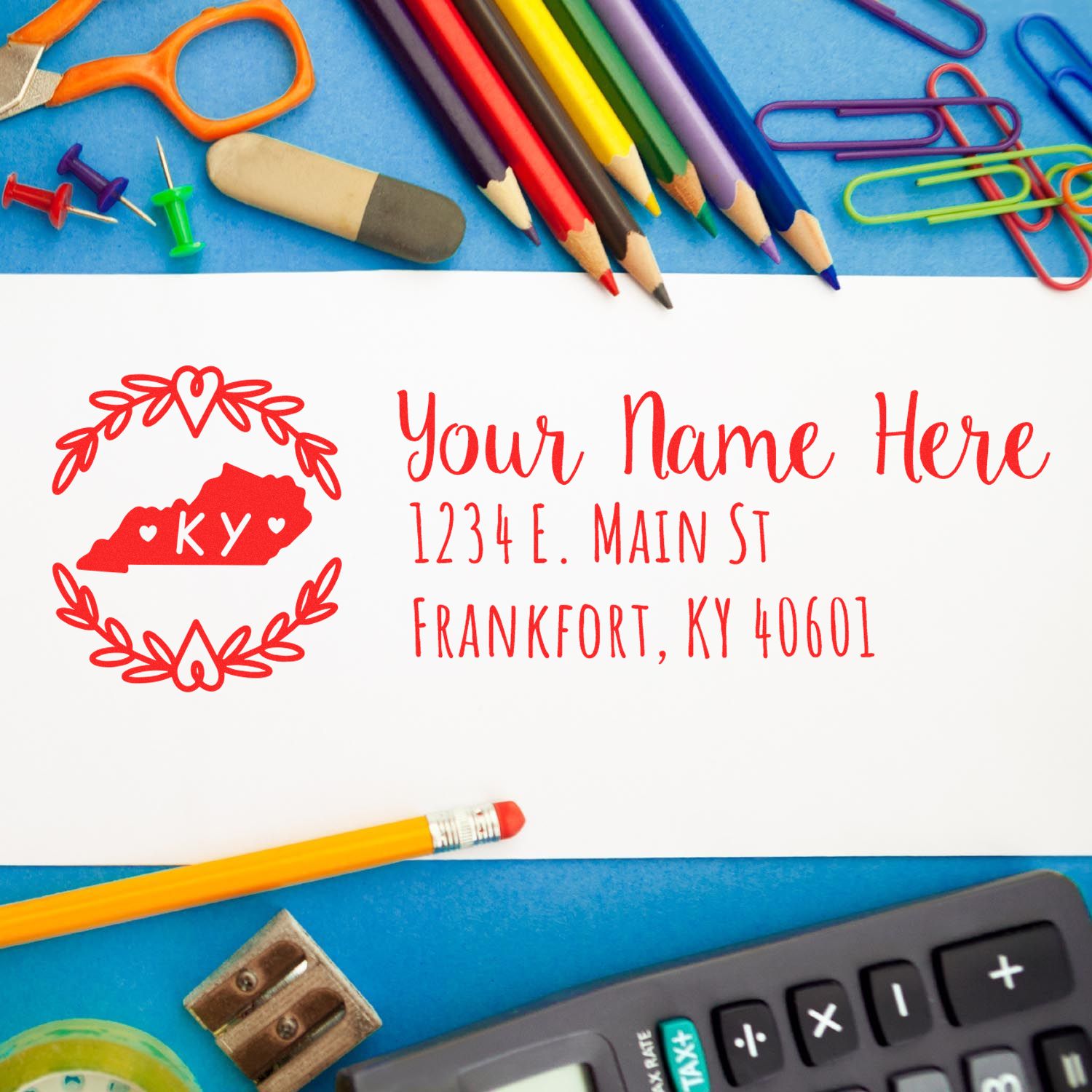 Kentucky State Custom Return Address Stamp on an envelope surrounded by colorful office supplies, including pencils, paper clips, and a calculator, showcasing a personalized address in red ink.