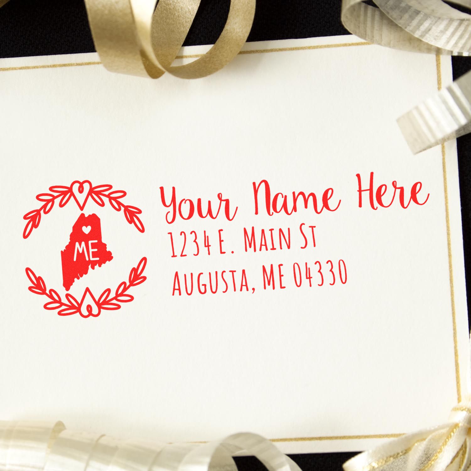 PSI Pre-Inked Maine State Customized Address Stamp on a card with a red design featuring a heart and ME inside a wreath, surrounded by gold and silver ribbons.