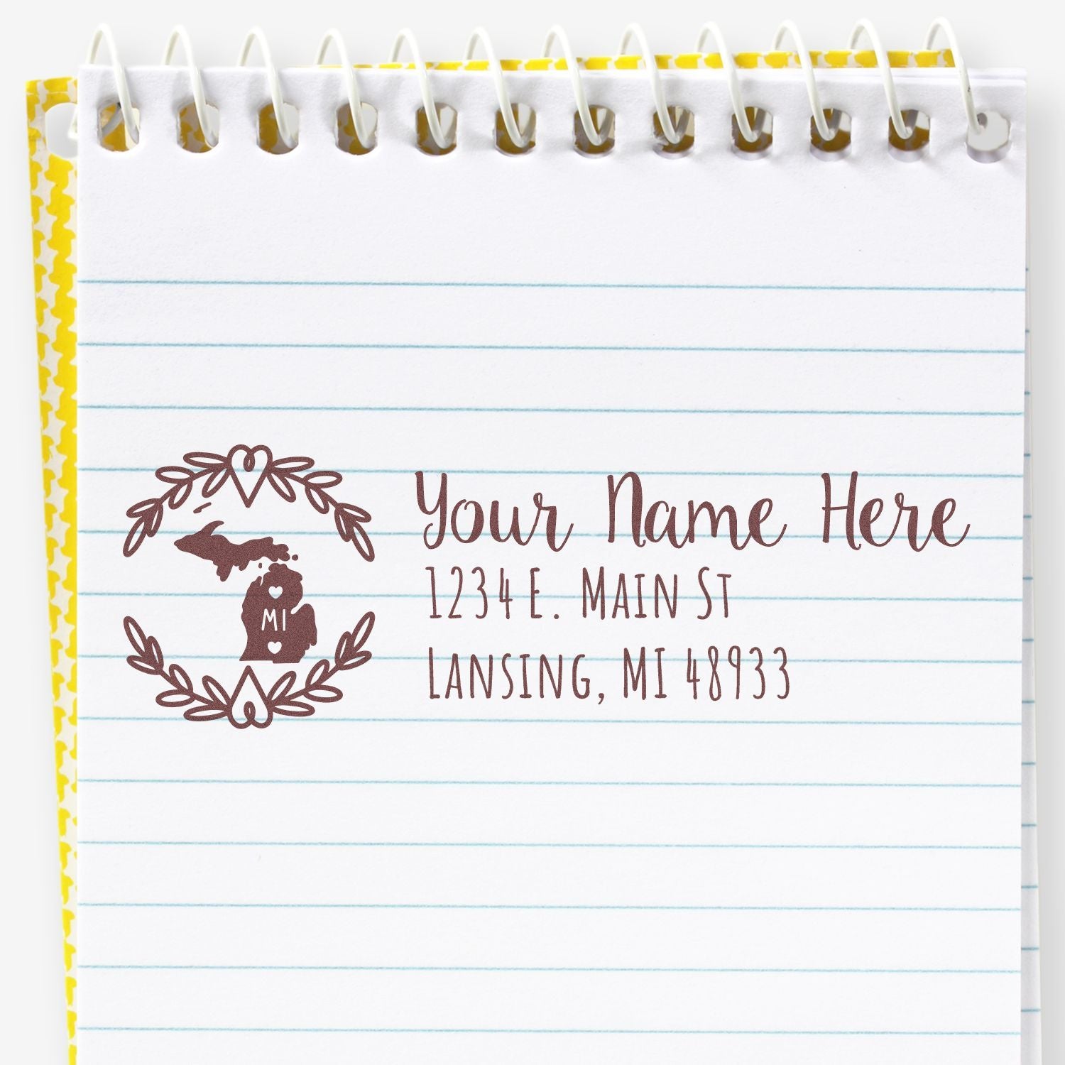 Michigan State Custom Return Address Stamp on a notepad, featuring a heart and state outline design with placeholder text for name and address in brown ink.