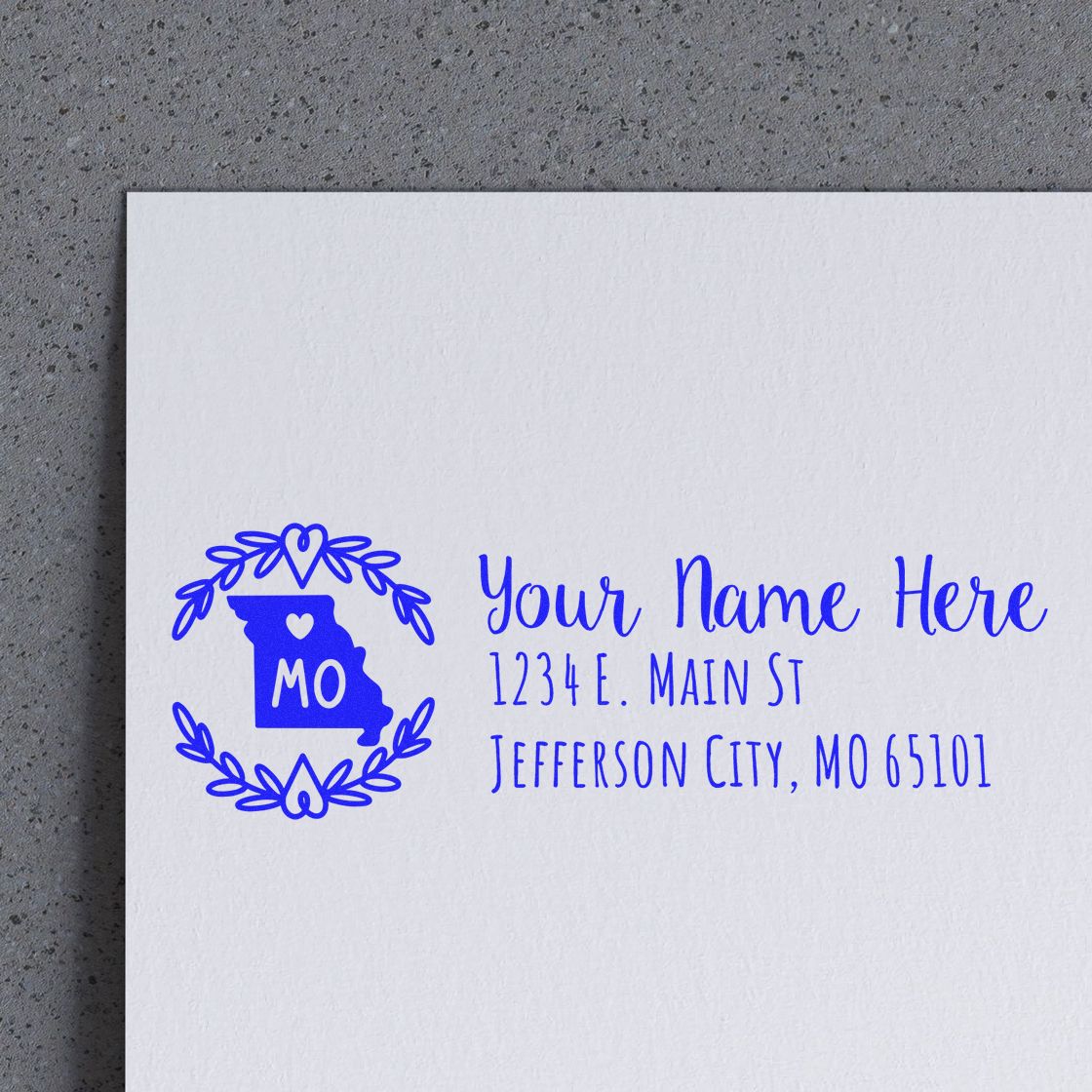 Missouri State Custom Return Address Stamp on an envelope, featuring a blue Missouri outline with heart and laurel design, personalized with name and address in elegant script.