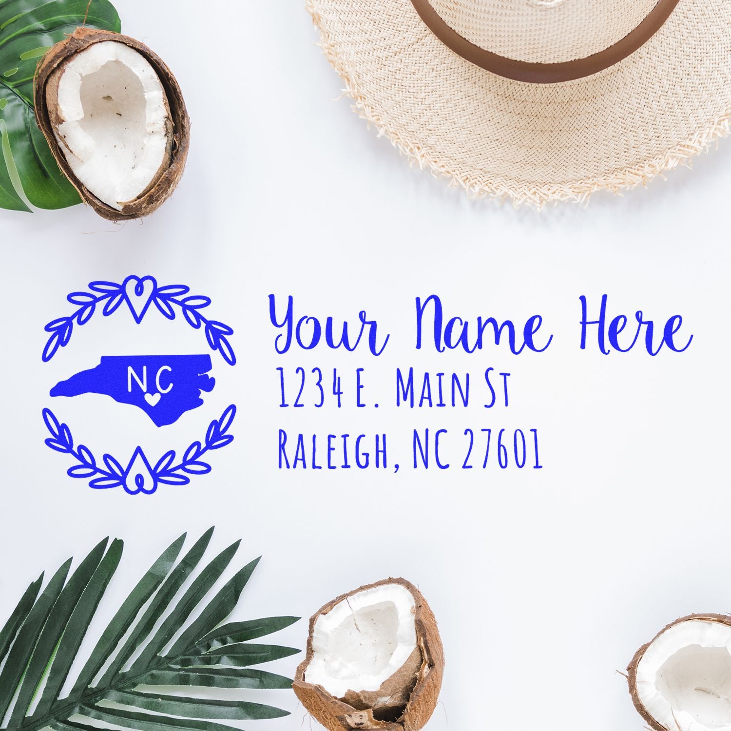 North Carolina State Custom Return Address Stamp on white surface with palm leaves, hat, and coconut halves. Features state outline and sample address in blue ink.