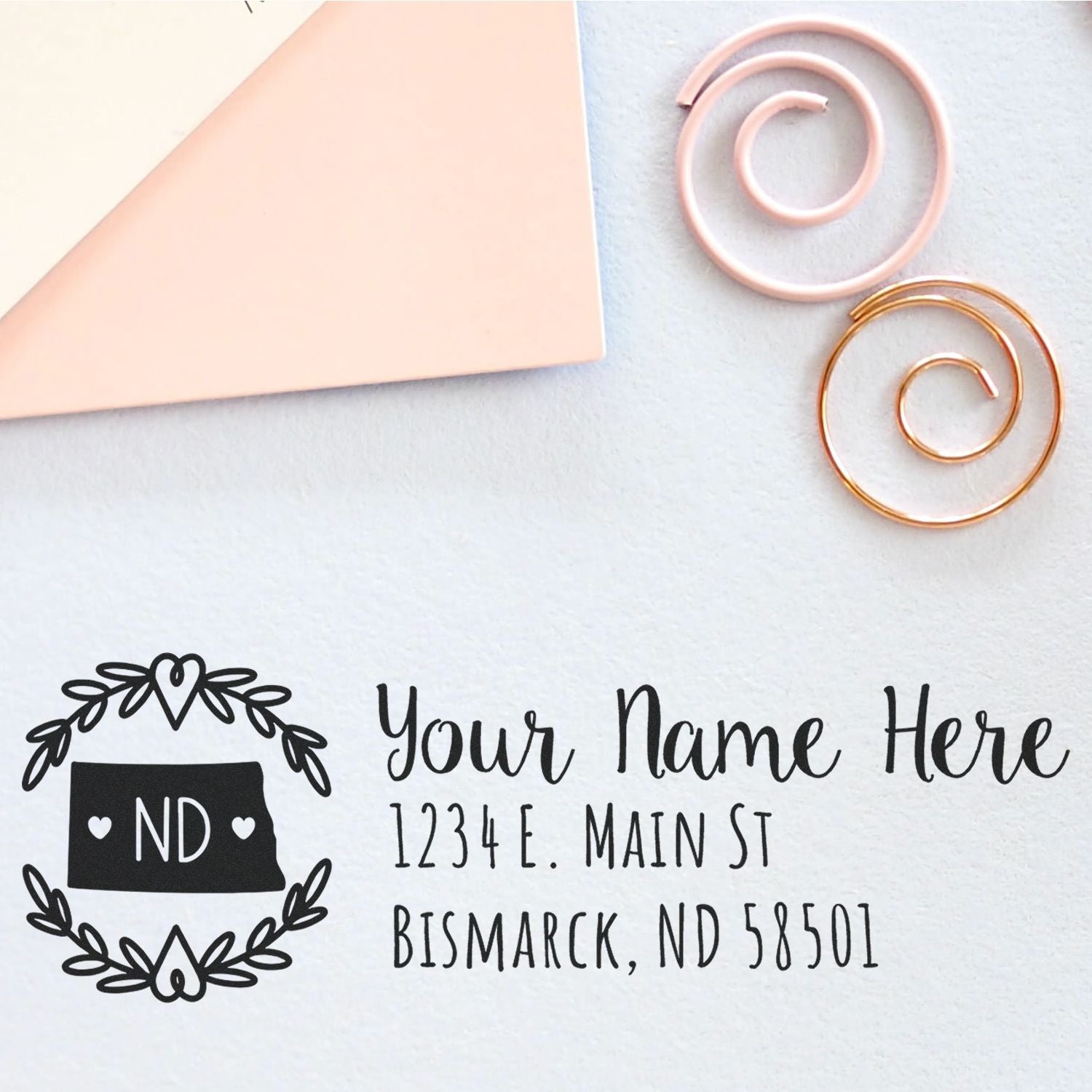 North Dakota State Custom Return Address Stamp on a light surface with decorative spirals, featuring a sample address in elegant font.