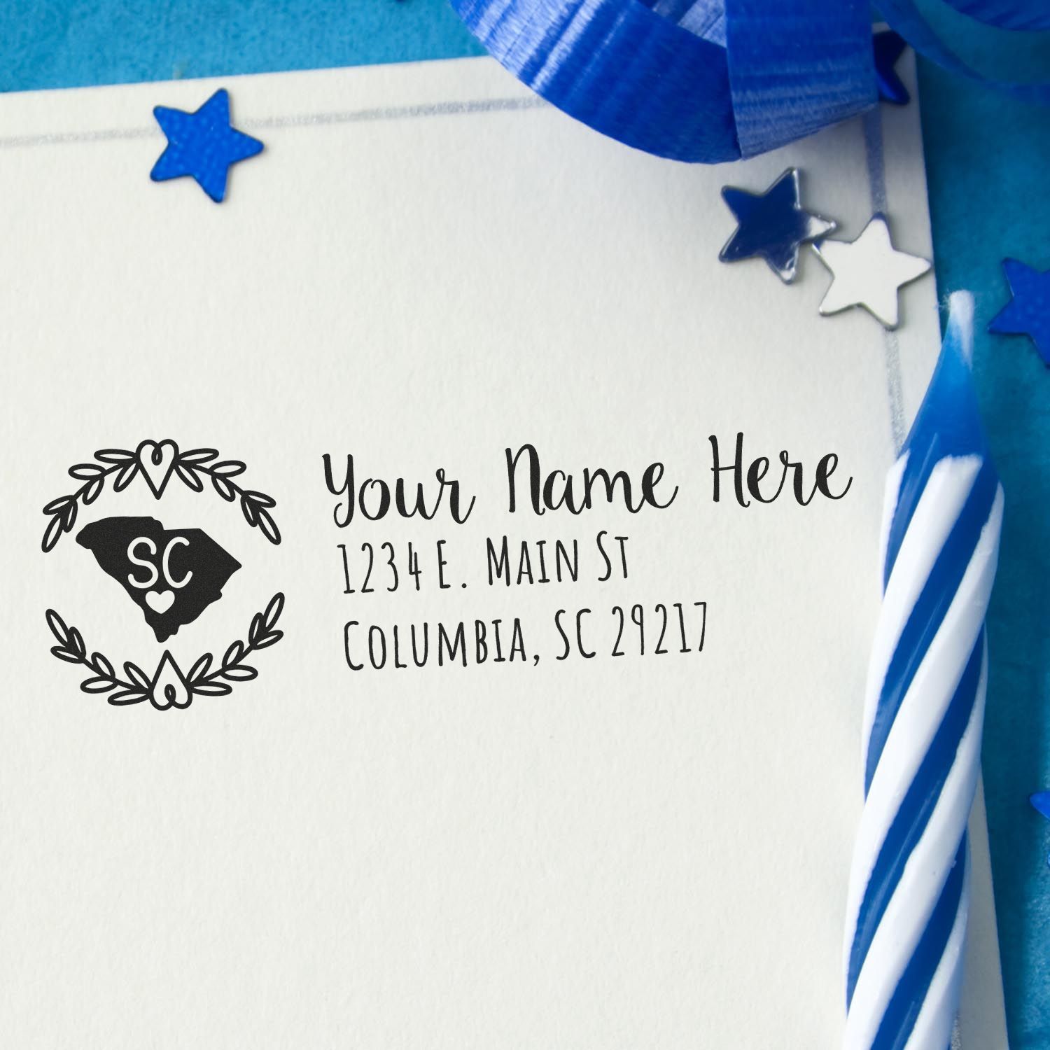 South Carolina State Custom Return Address Stamp on an envelope with a decorative state outline and address. Blue ribbon and stars add a festive touch.