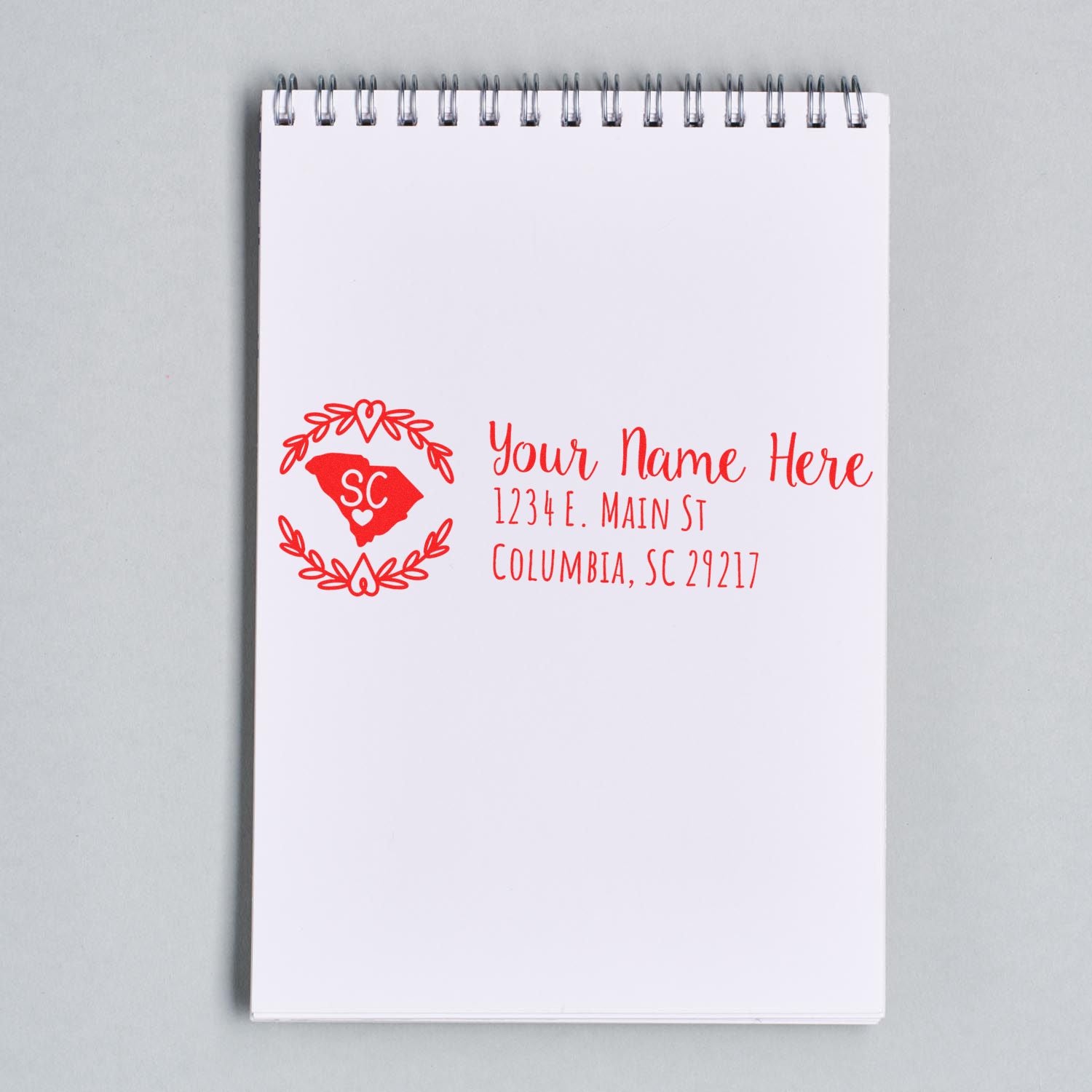 Notepad displaying a [South Carolina State Custom Return Address Stamp] with a red heart and laurel design, featuring placeholder text for name and address in Columbia, SC.