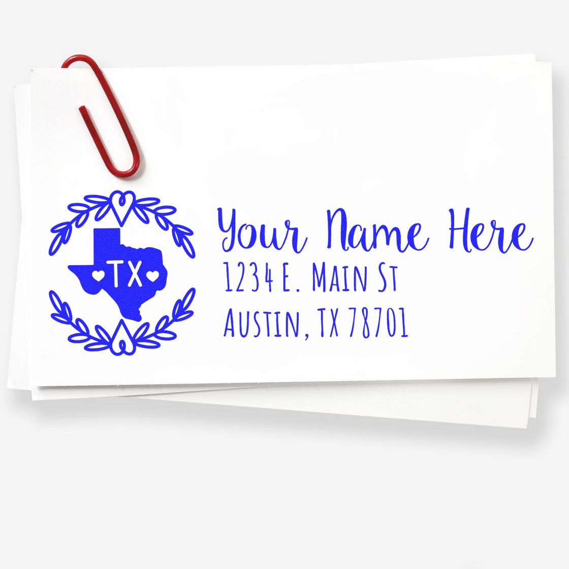 Texas State Custom Return Address Stamp on white envelope with blue ink, featuring a Texas outline and decorative border. A red paperclip holds the envelope.