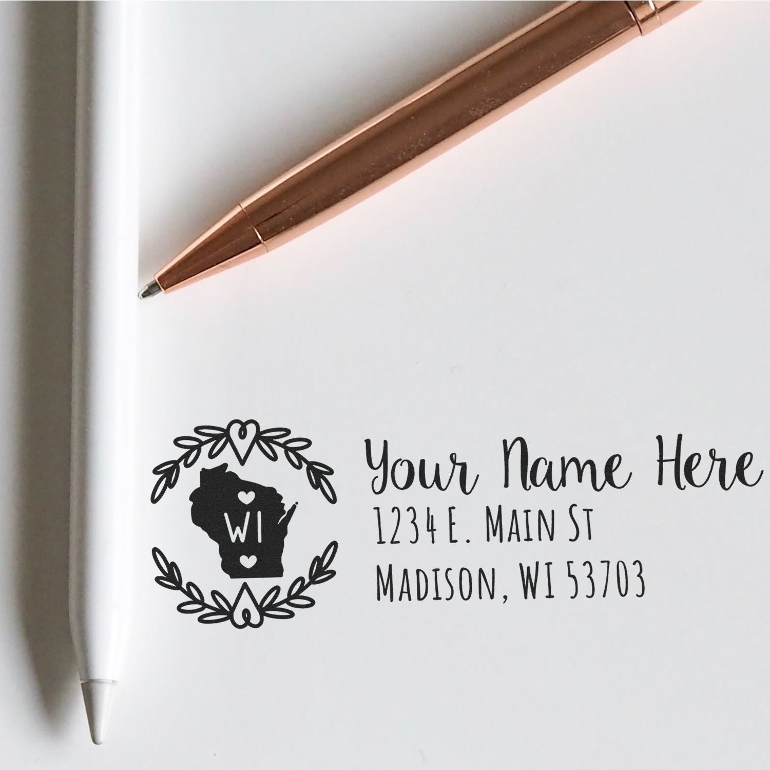 PSI Pre-Inked Wisconsin State Customized Address Stamp on white paper, featuring a Wisconsin outline with floral design, next to a rose gold pen.